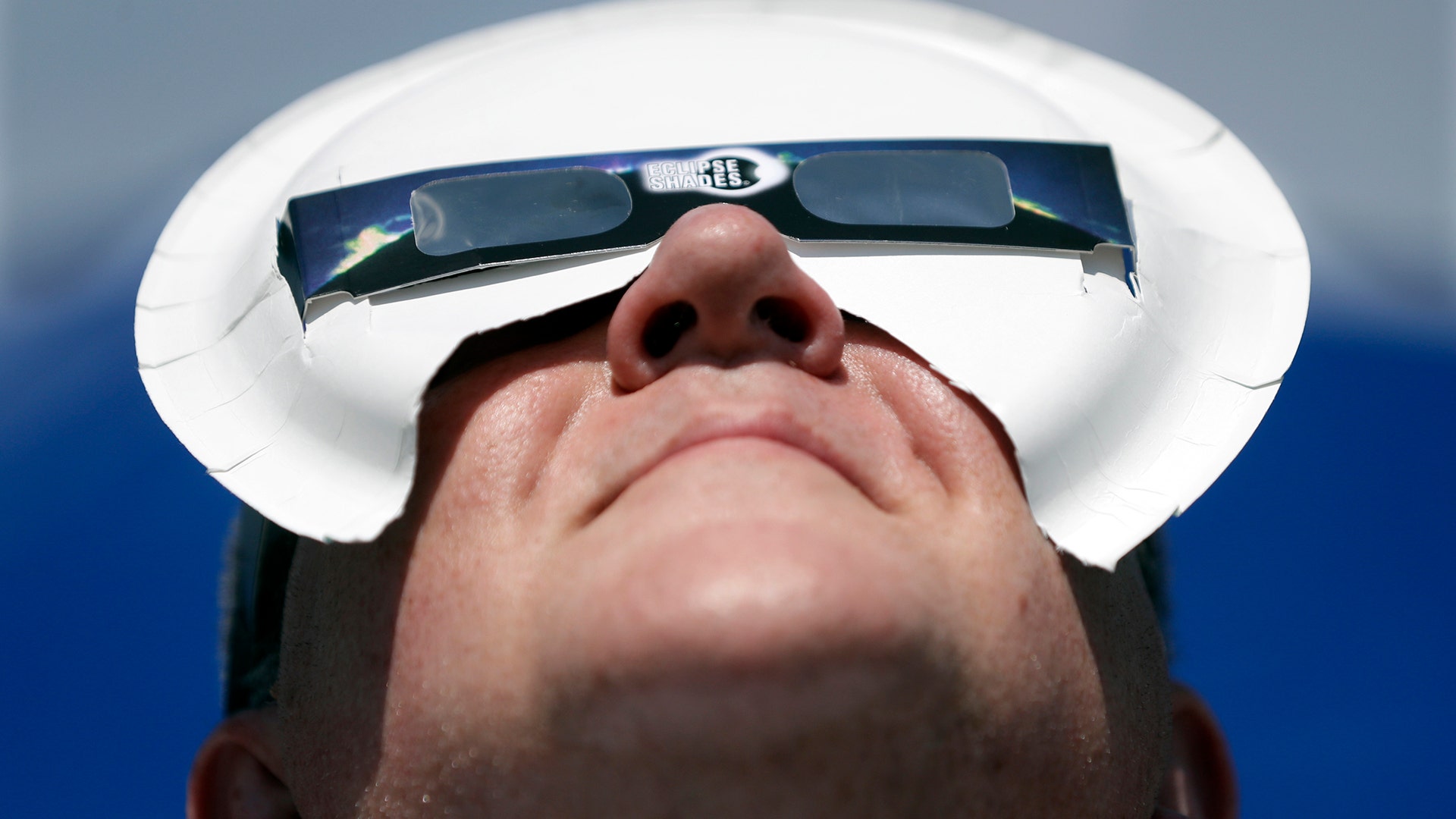 Tim Burt uses a paper pate to hold his solar eclipse viewing glasses in place in Hopkinsville, Kentucky