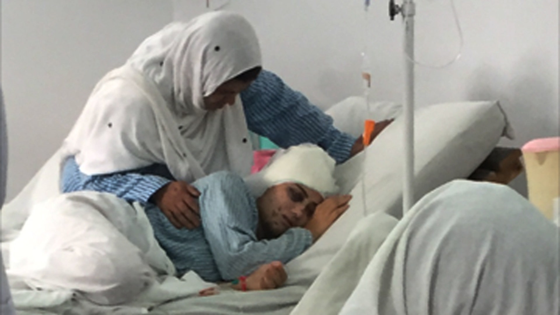 A young woman, writhes in agony and moans. Her body was battered with bullets from an AK-47 in the backseat of her family's car 