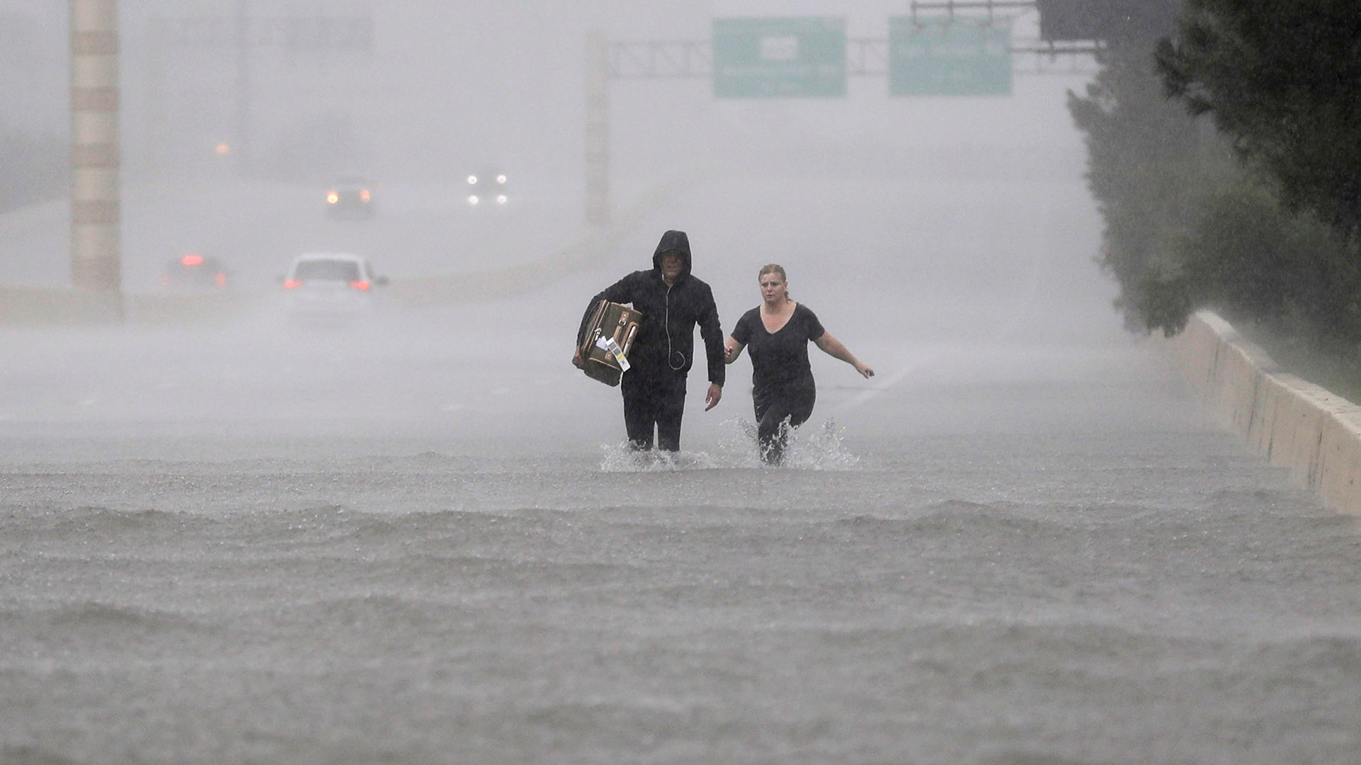Two people walk down a flooded section of Interstate 610 in floodwaters from Tropical Storm Harvey on Sunday in Houston, Texas