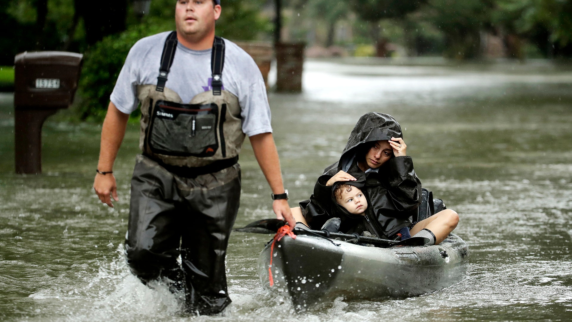 People evacuate a neighborhood in west Houston inundated by floodwaters from Tropical Storm Harvey on Monday