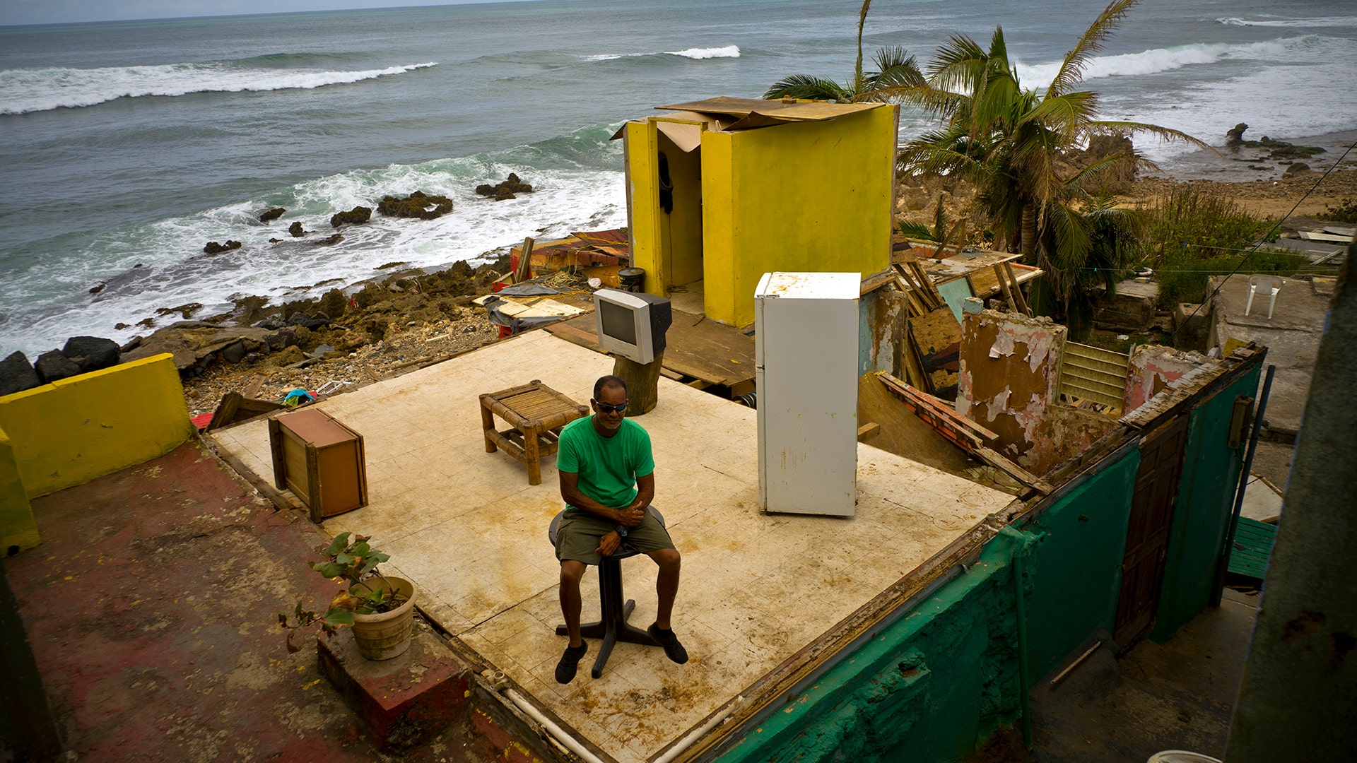  Roberto Figueroa Caballero sits on a small table in his home that was destroyed by Hurricane Maria in San Juan, Puerto Rico, October 5, 2017