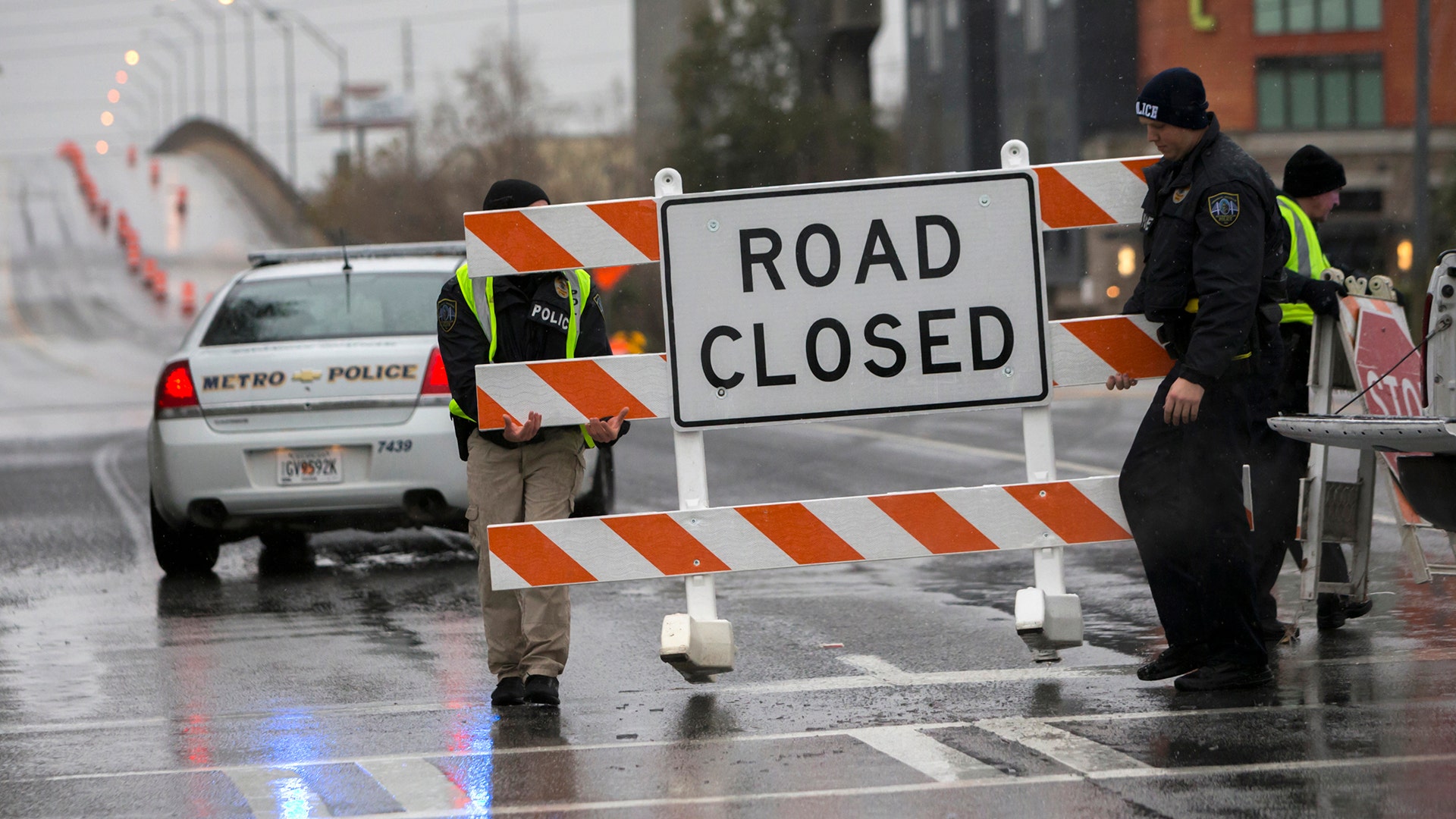 Two Savannah Chatham Metro Police officers set up a barricade in front of a bridge that was closed due to ice on the road