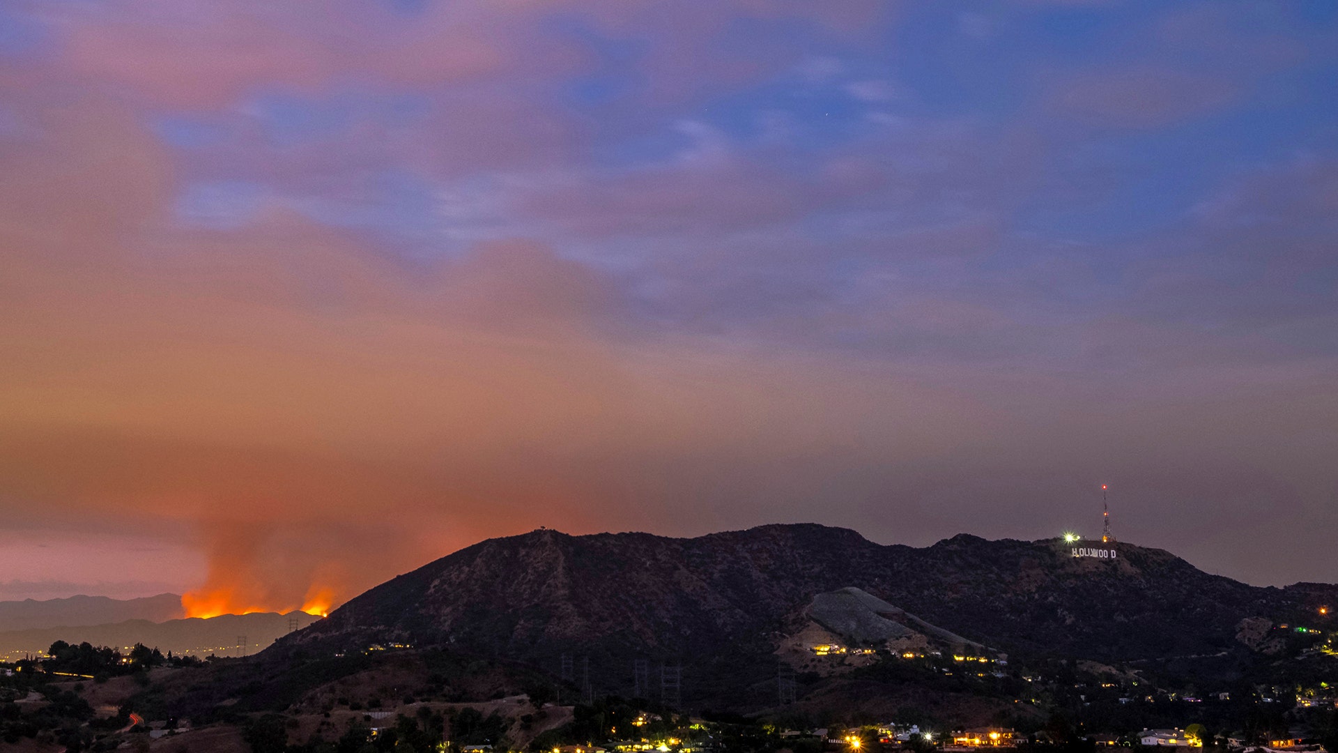 The La Tuna Fire burns as the Hollywood sign is seen at sunset in Los Angeles, September 1