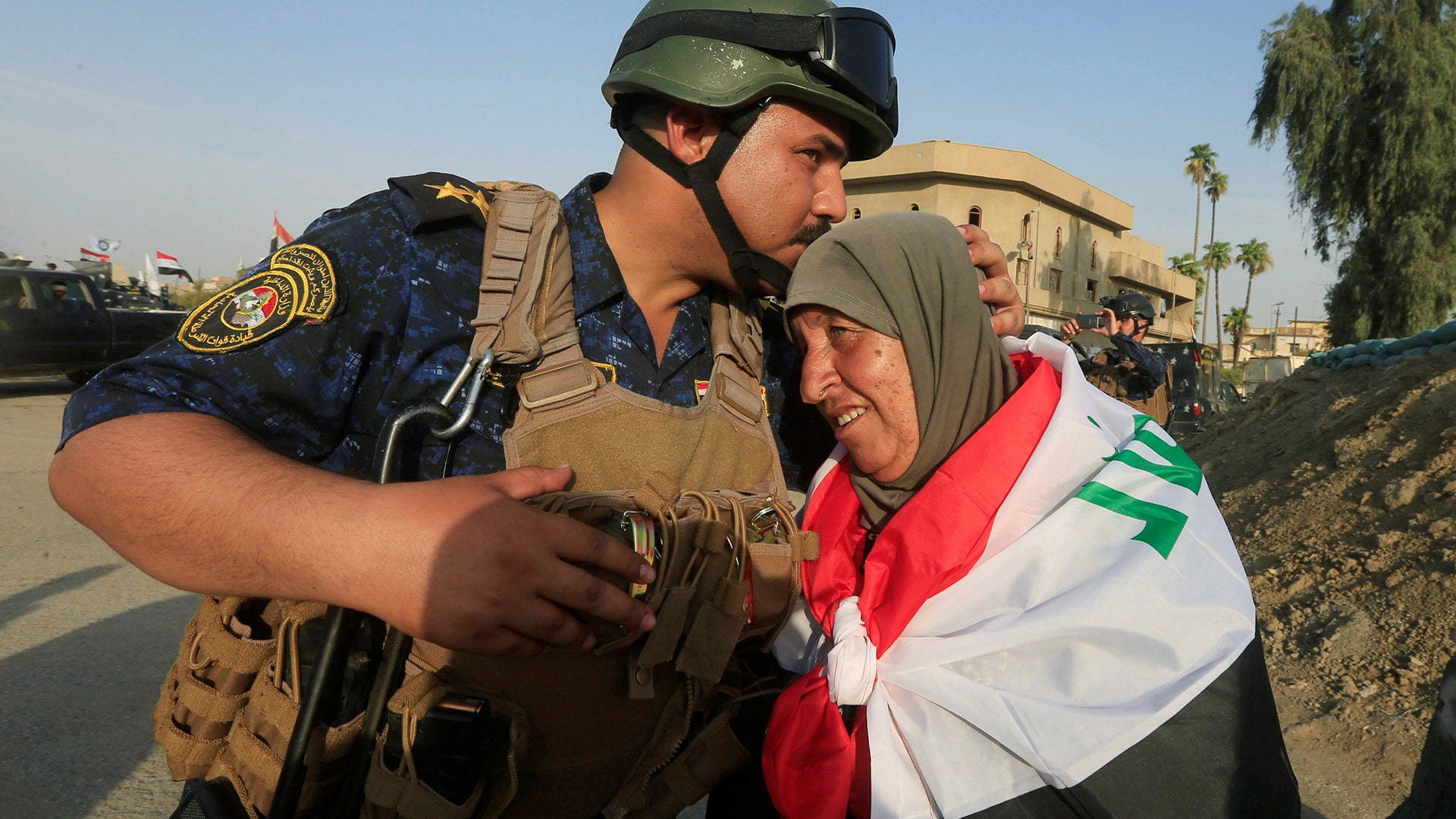 A member of Iraqi Federal police kisses an old woman in West Mosul, Iraq July 9