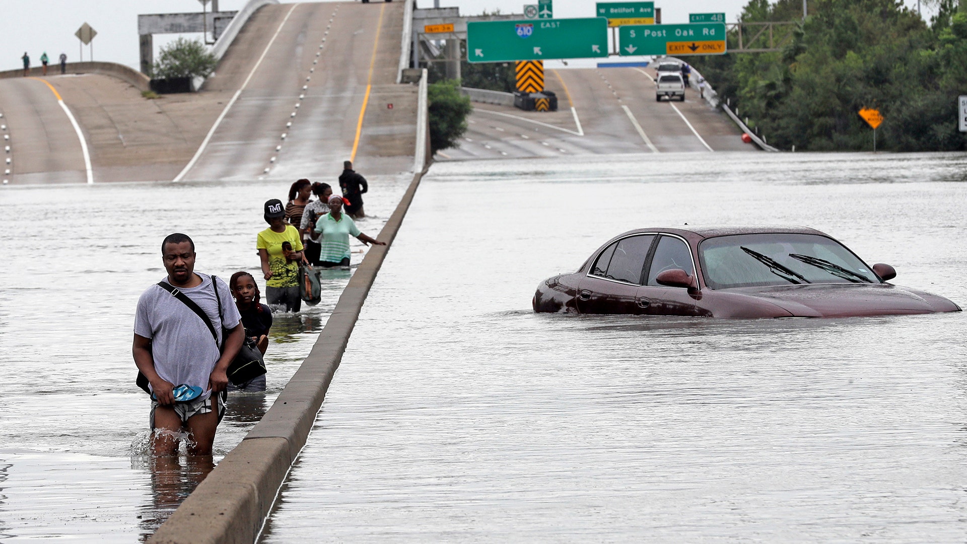 Evacuees wade down a flooded section of Interstate 610 as floodwaters from Tropical Storm Harvey rise Sunday in Houston