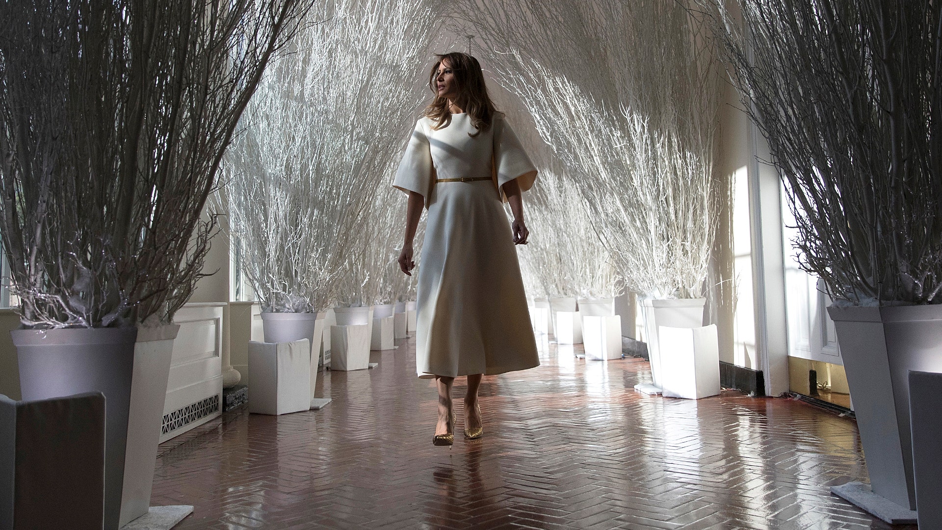 First lady Melania Trump walks along the East Colonnade of the White House, which has been decorated with the theme 
