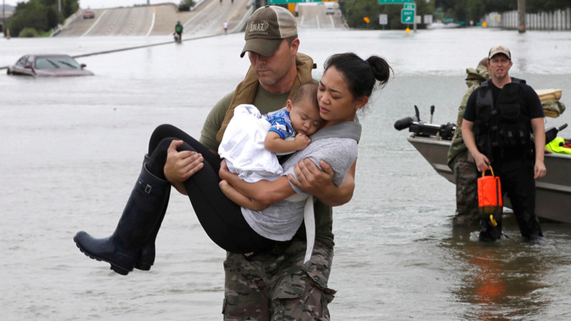  Houston Police SWAT officer Daryl Hudeck carries Catherine Pham and her son Aiden after rescuing them in Houston, Sunday