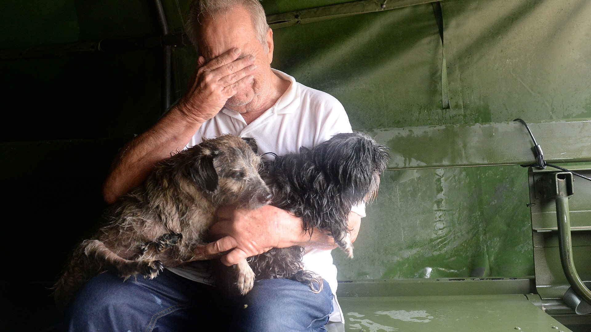 An evacuee holding two dogs reacts after his rescue by Texas National Guardsmen in Cypress Creek, Houston, Tuesday