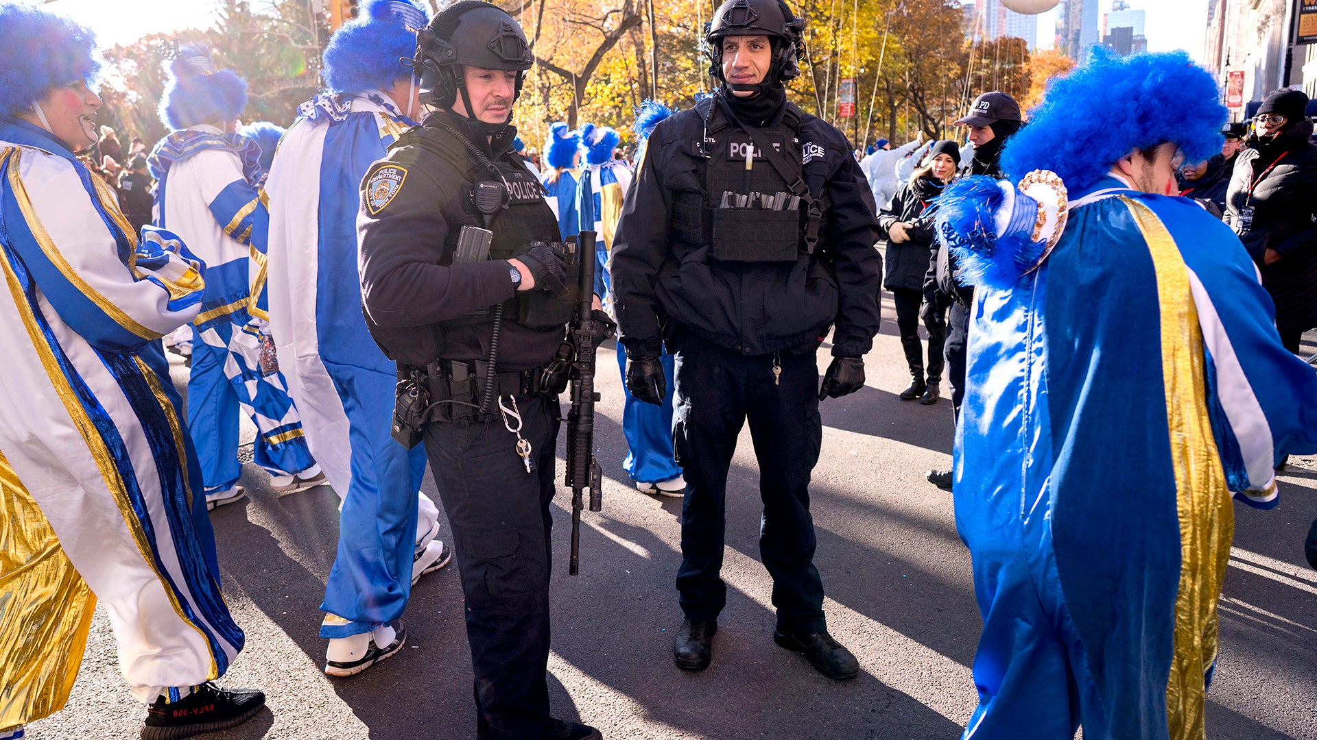 New York Police Department officers hold their position as parade participants walk around
