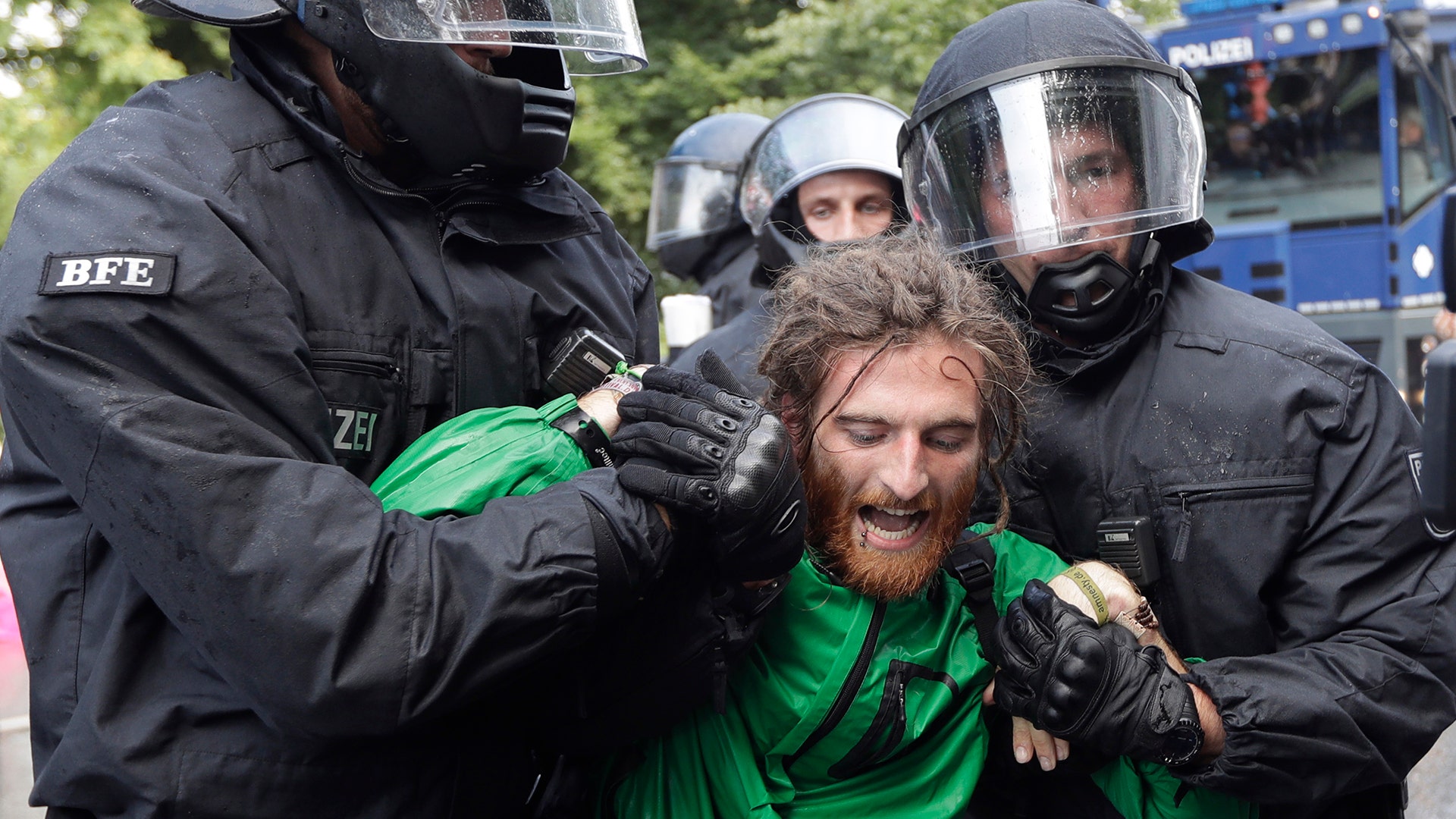Police officers carry a demonstrator who blocked a street on the first day of the G-20 summit in Hamburg, Germany, Friday