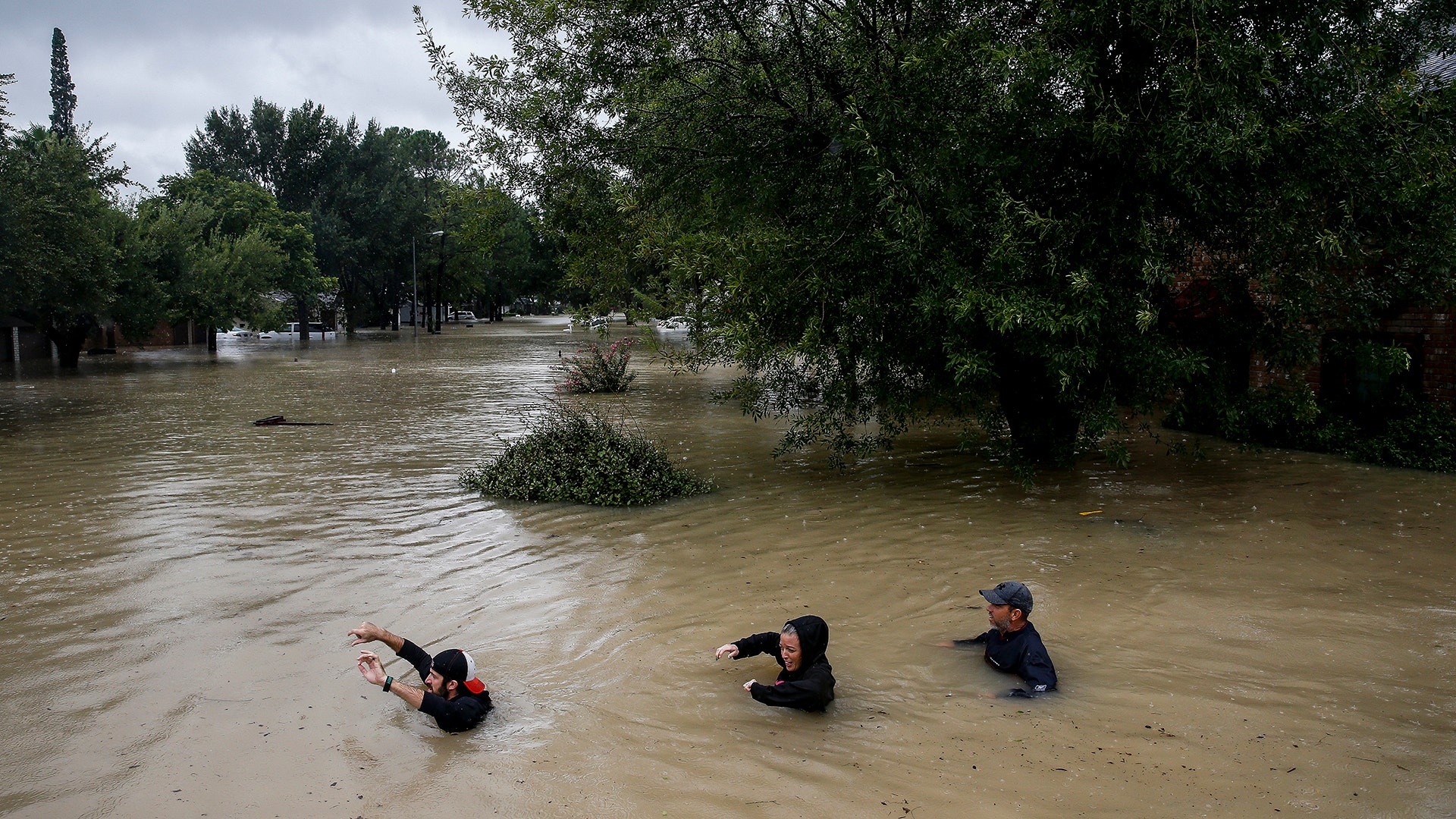 People wade through chest deep water down Pine Cliff Drive as Addicks Reservoir nears capacity in Houston, Tuesday