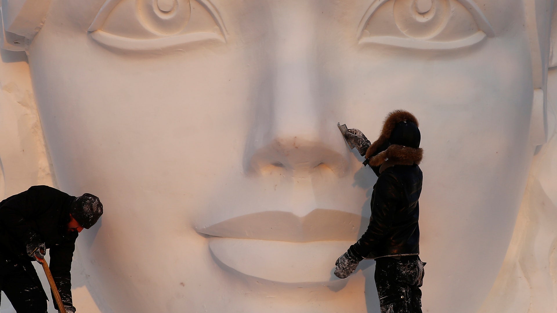 Artists prepare a snow sculpture.
