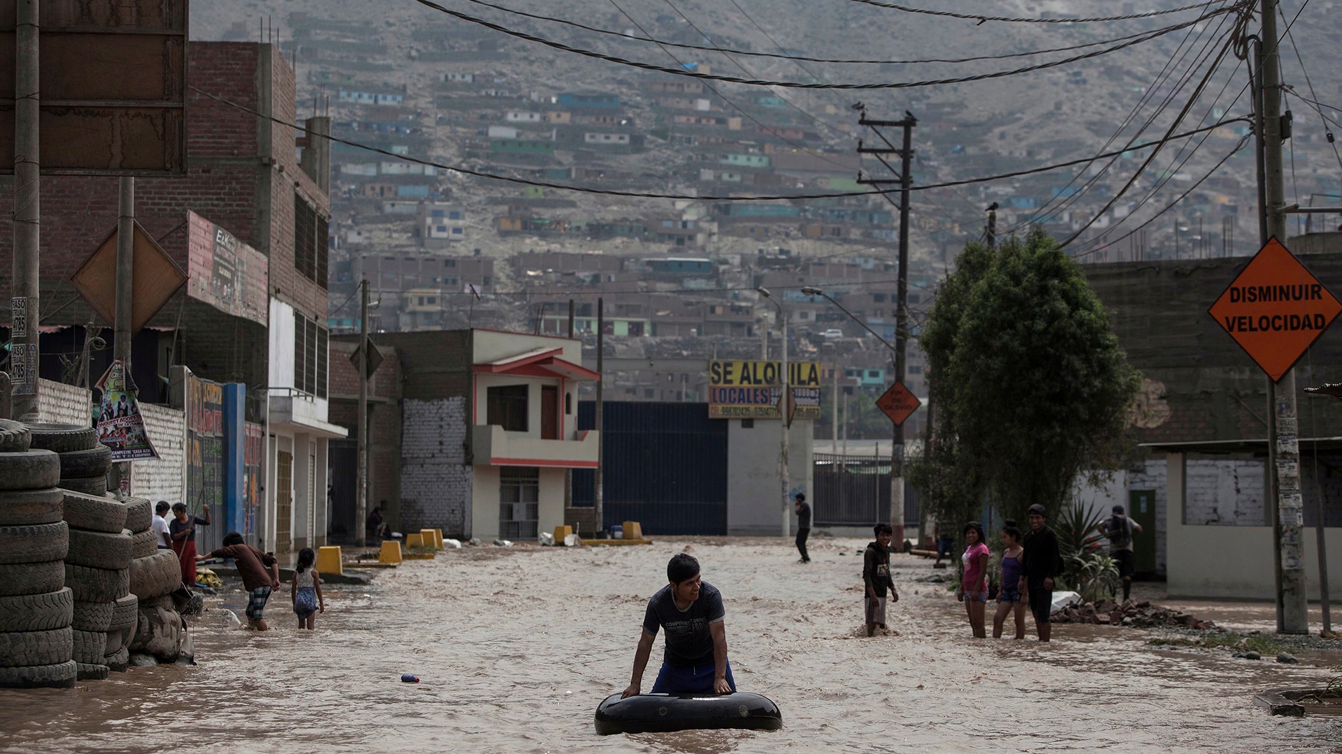 A man plays in a flooded street using an inner tube in Lima, Peru.