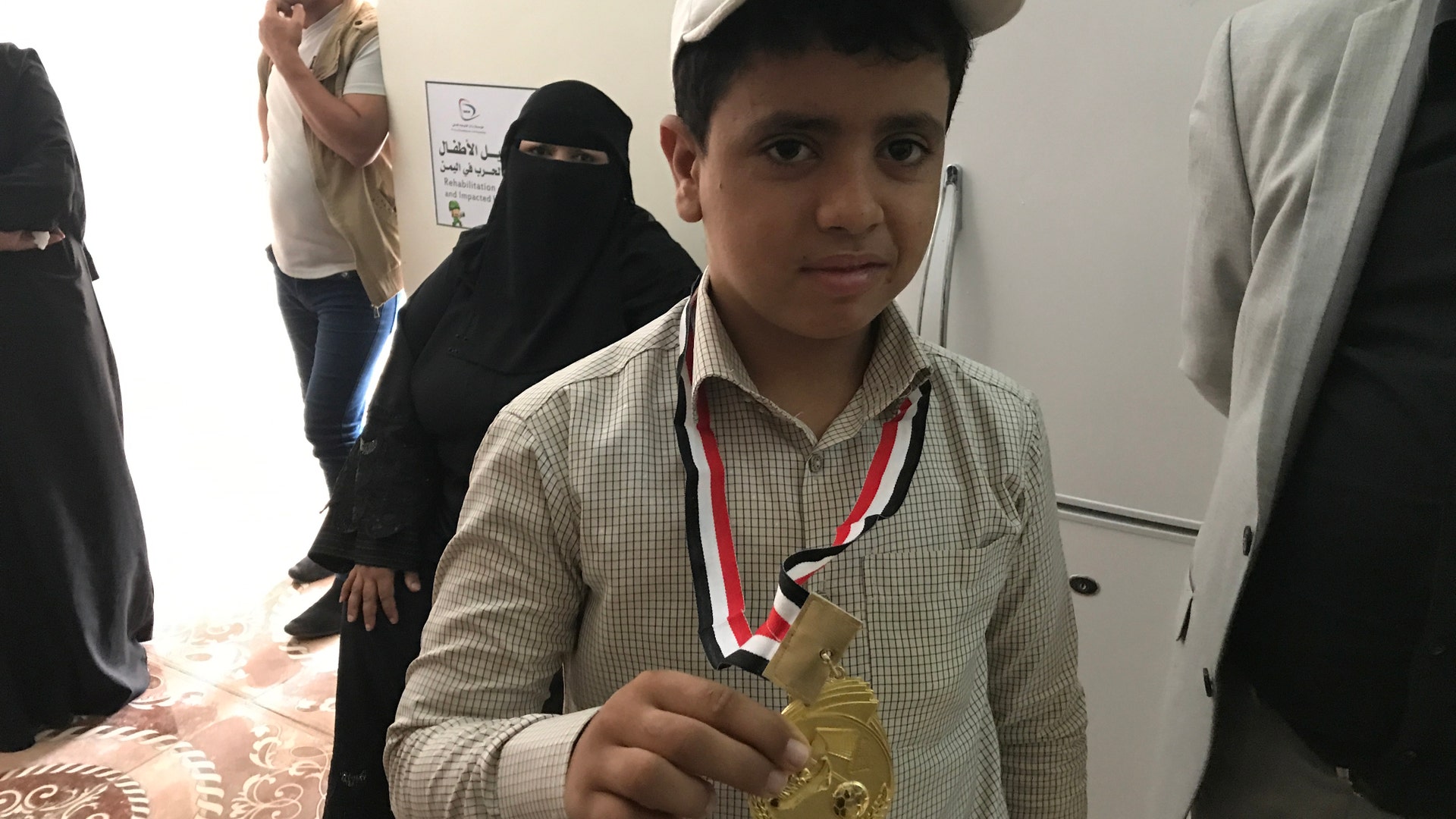 A young student shows off his medal among counselors and staff at the KS Relief Center in Yemen.