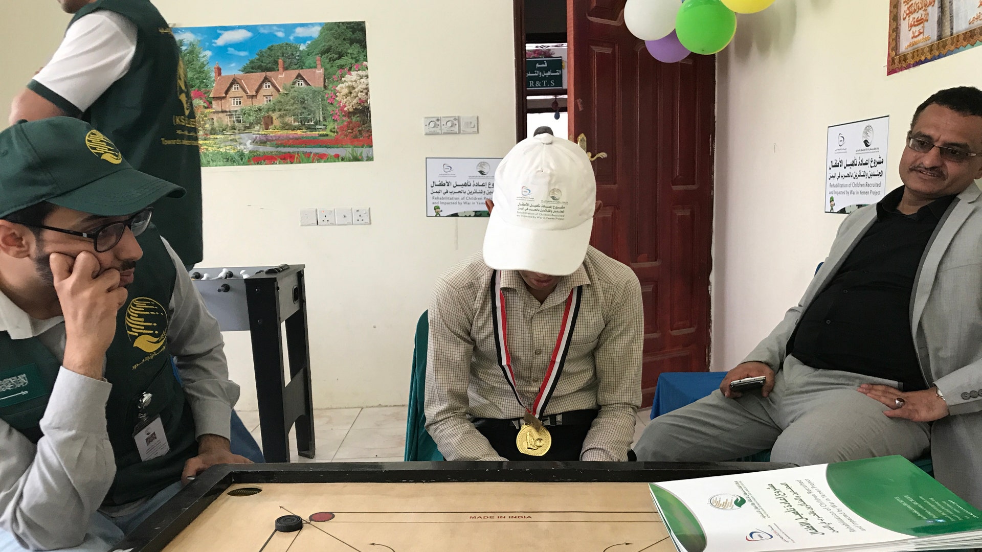 A student plays a board game with counselors and staff at the KS Relief Center in Yemen.