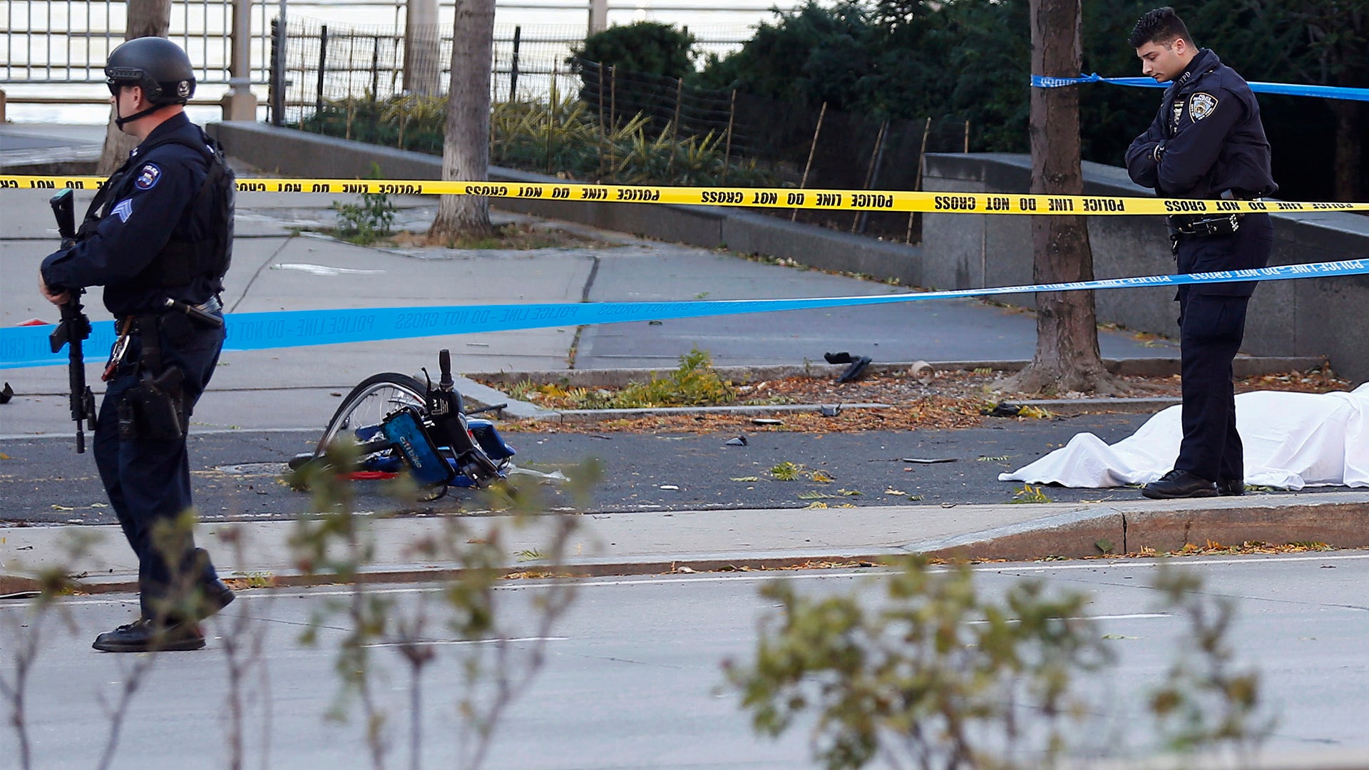 Police officers stand next to a body covered under a white sheet near a mangled bike in New York City, October 31
