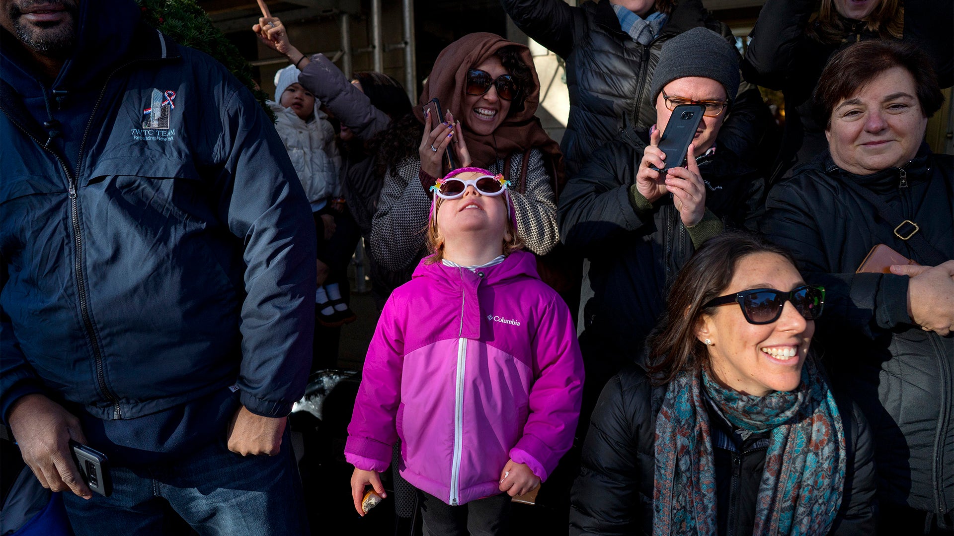 Adults and children along Central Park West watch a passing balloon during the Macy's Thanksgiving Day Parade