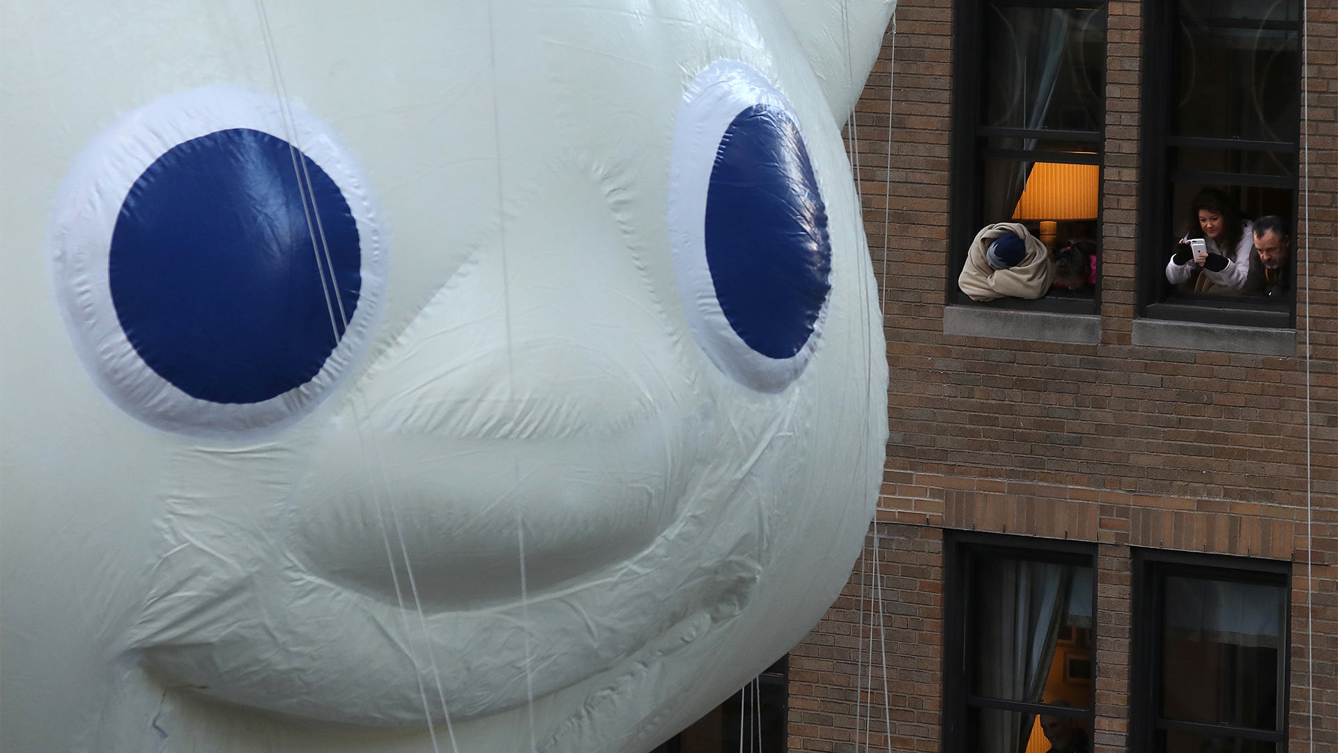 People take photos of the Pillsbury Dough Boy balloon as it takes part in the Thanksgiving Day 