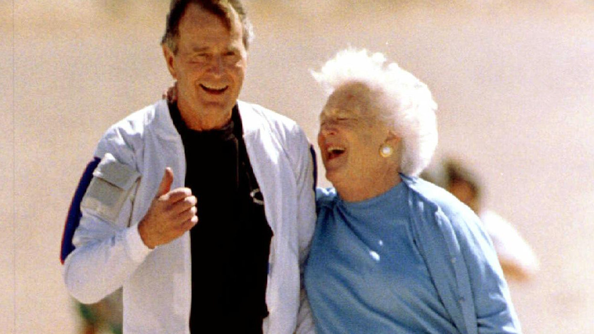 Former President George Bush gives a thumbs up with his wife Barbara at his side, after a successful parachute jump 