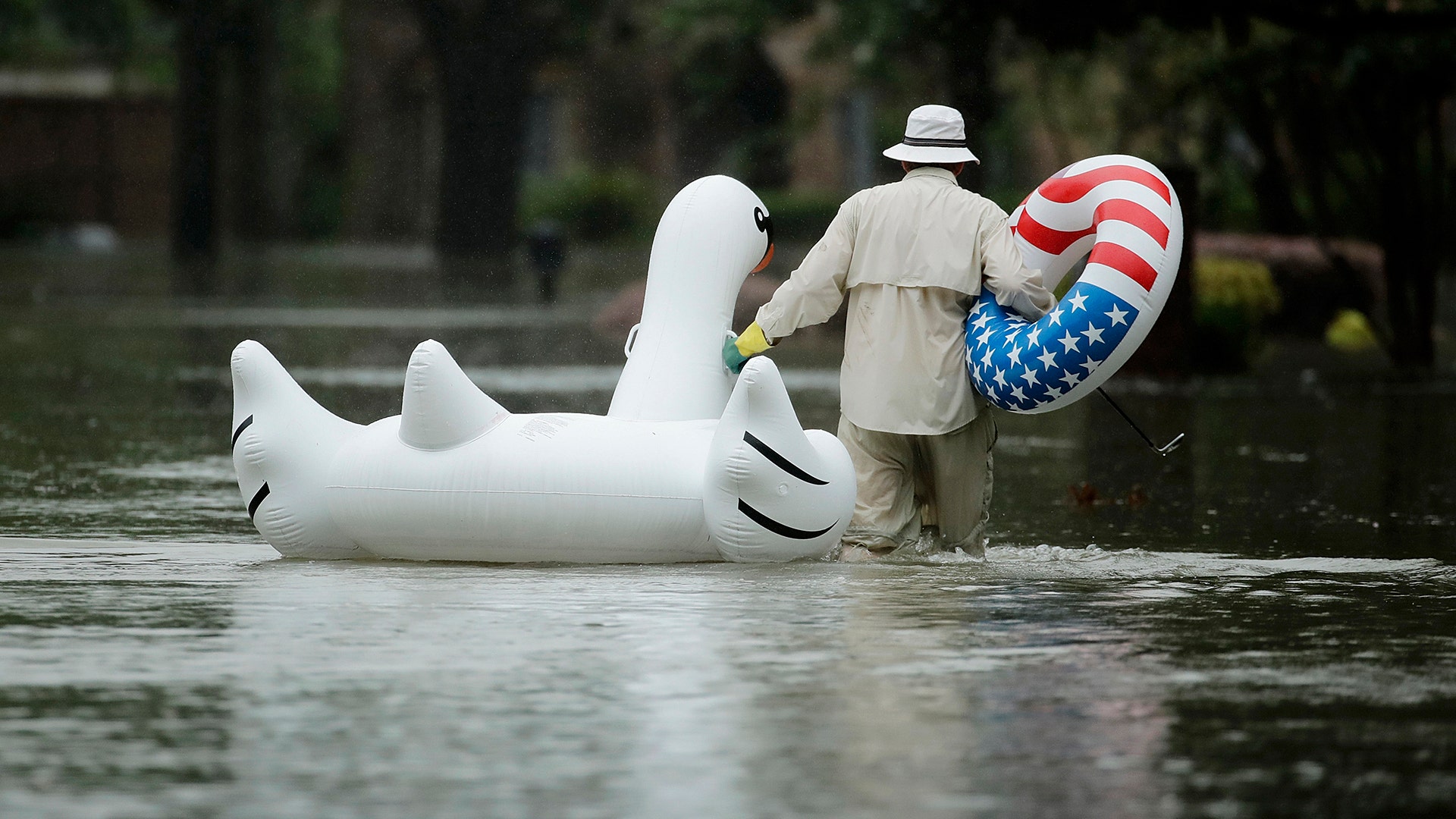 A man walks to his home in a neighborhood inundated by floodwaters from Tropical Storm Harvey on Monday