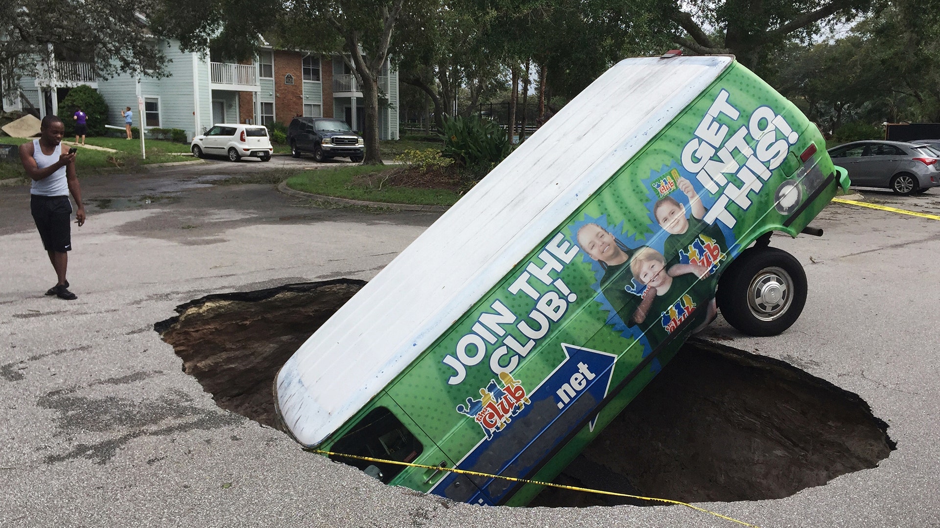 A boy photographs a van in a sinkhole in Winter Springs, Fla., Monday