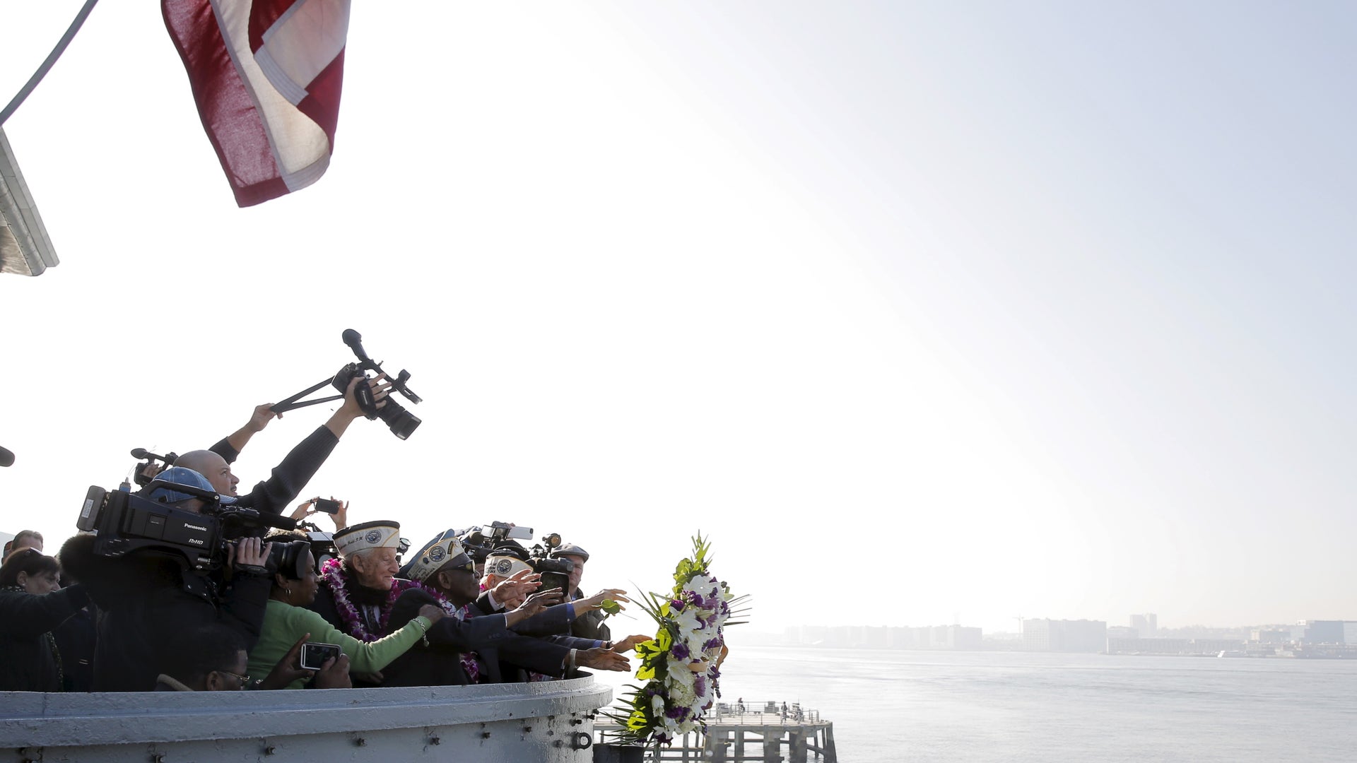 Pearl Harbor survivors toss a commemorative wreath off the fantail of the USS Intrepid 