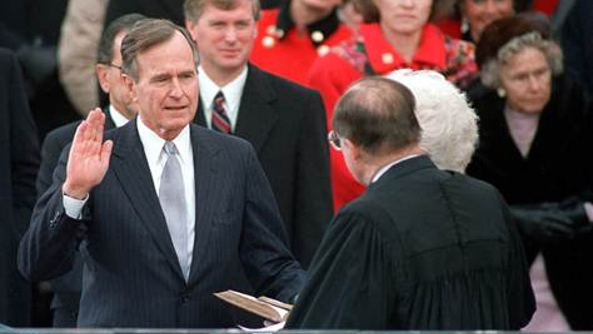 President George H. W. Bush raises his hand as he takes the oath of office as President of the United States outside the Capitol on Jan. 20, 1989, Washington, D.C. 