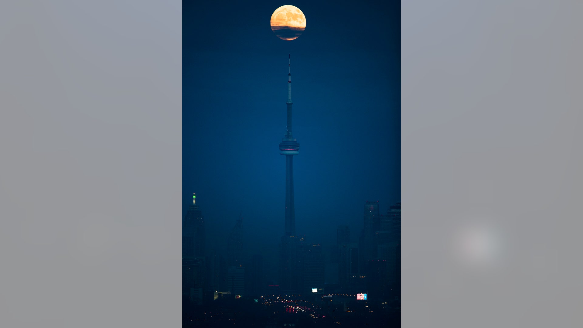 The moon rises over the CN Tower and skyline in Toronto, Ontario, December 2