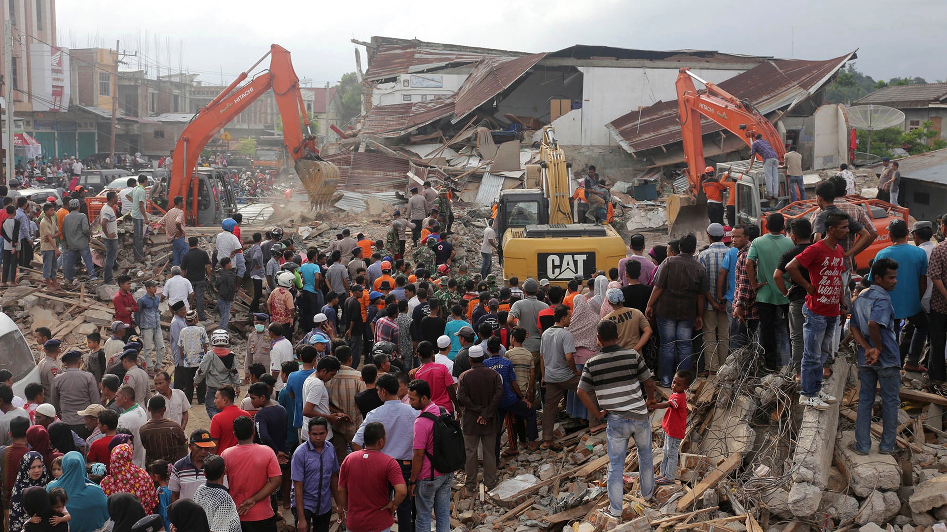 Rescuers use excavators to search for victims under the rubble of collapsed buildings after an earthquake in Pidie Jaya, Aceh province, Indonesia.