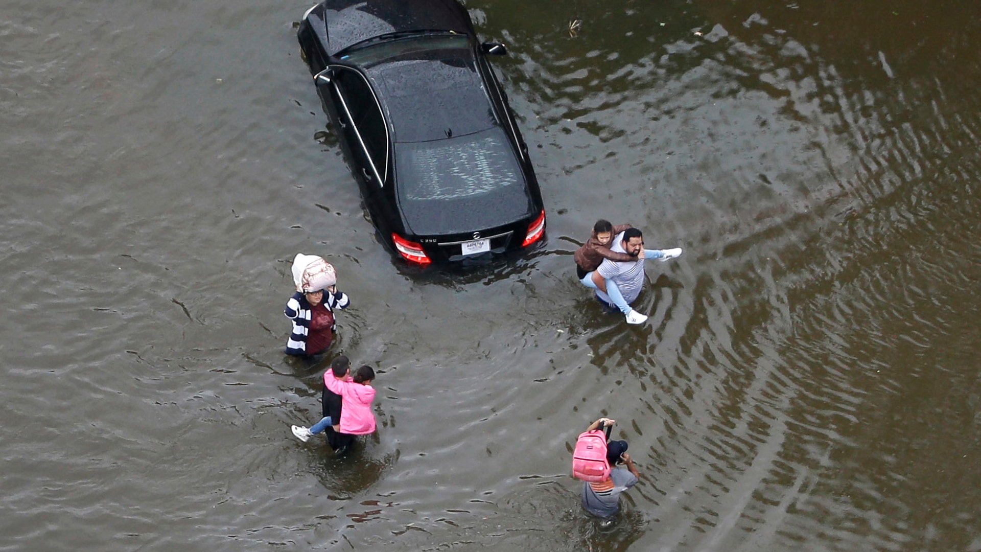 Residents wade through floodwaters as they evacuate their homes as floodwaters from Tropical Storm Harvey rise Tuesday, in Houston