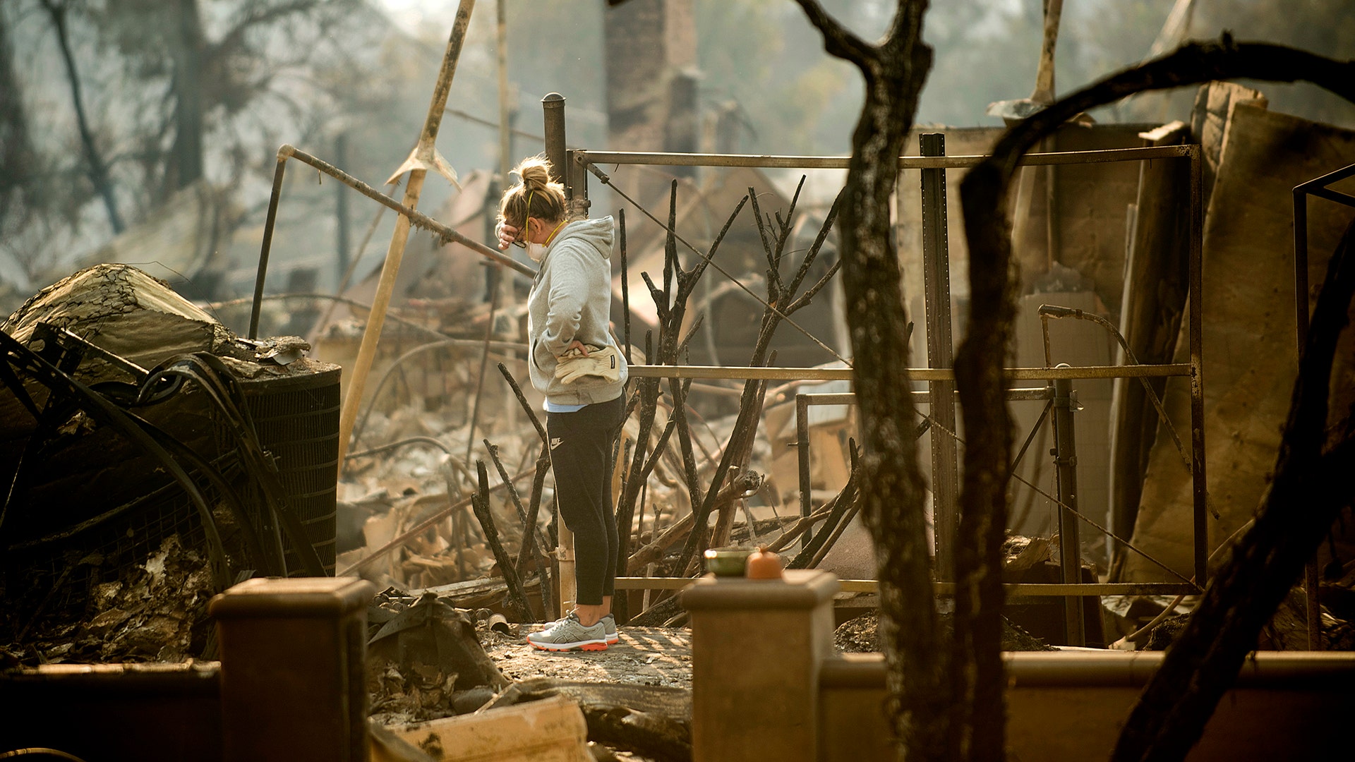 Bree Laubacher pauses while sifting through rubble at her Ventura, Calif., home following a wildfire, Wednesday