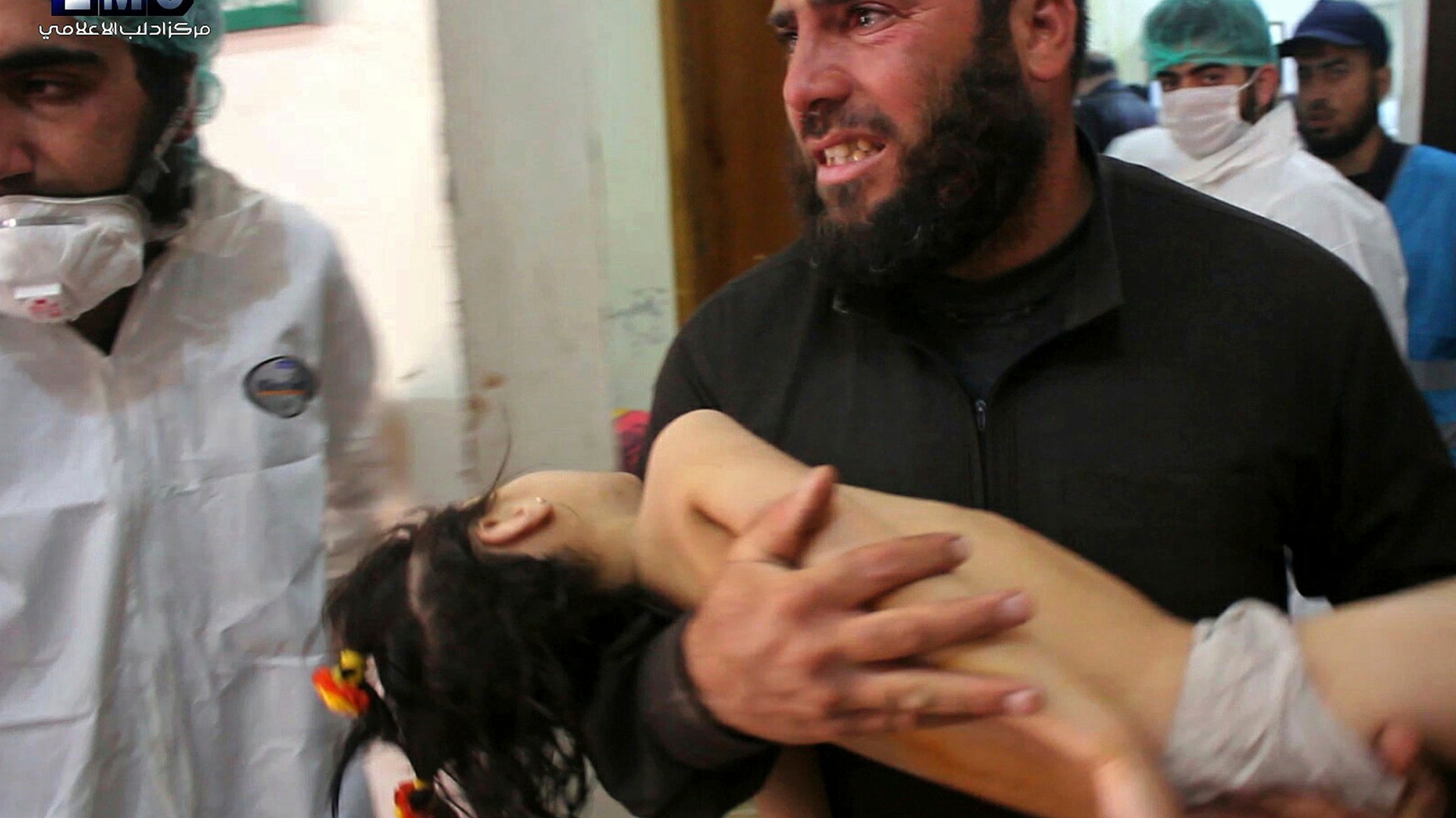 Man carrying a child following a suspected chemical attack at a makeshift hospital in the town of Khan Sheikhoun