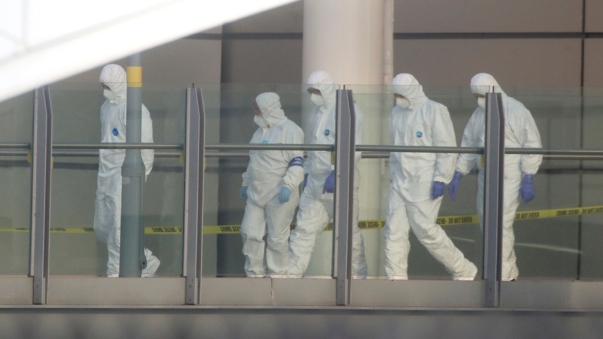 Police forensic investigators walk along a bridge linking Victoria Station with the Manchester Arena 