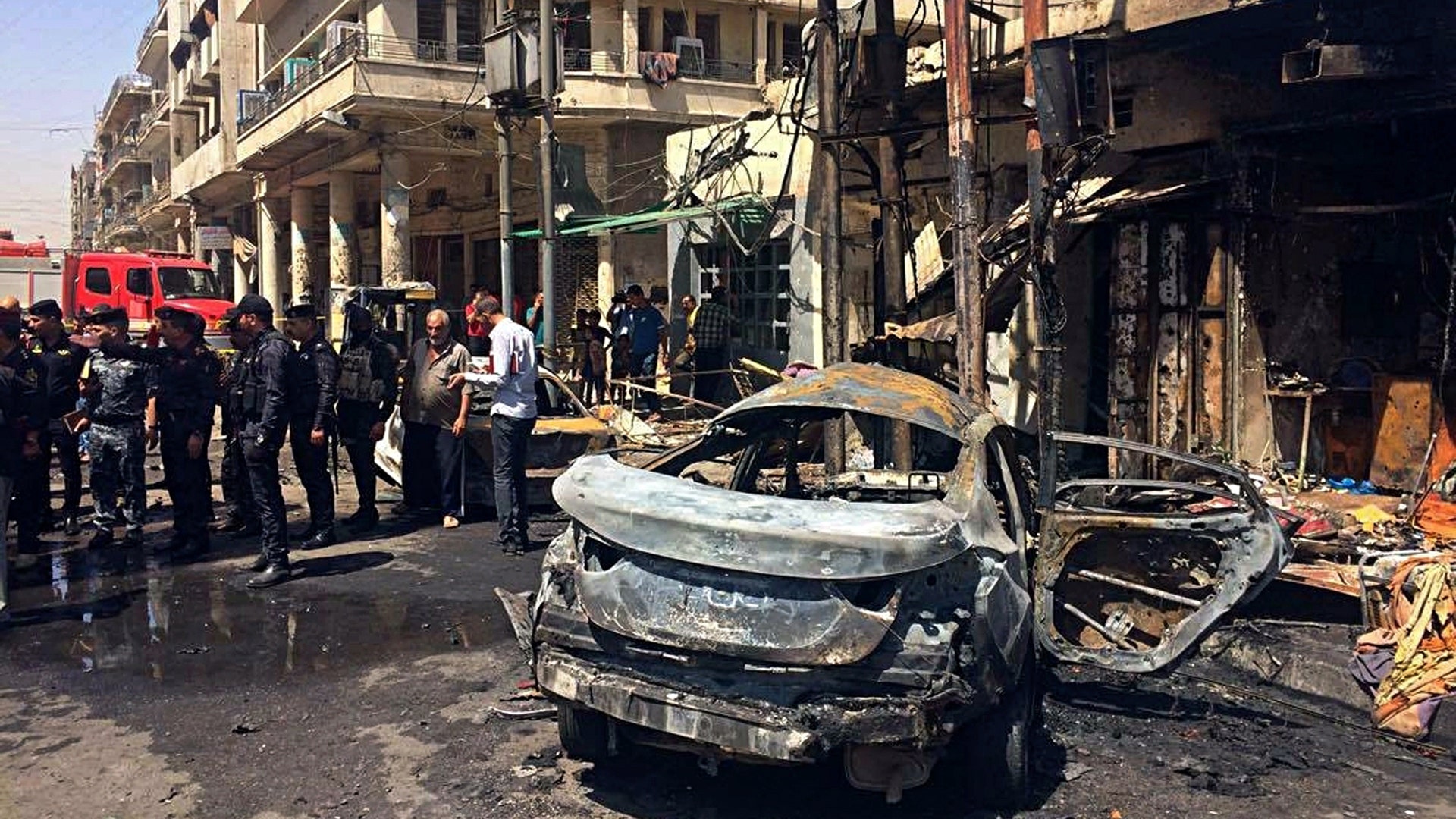 Iraqi security forces and civilians inspect the site of the deadly bombing in Baghdad
