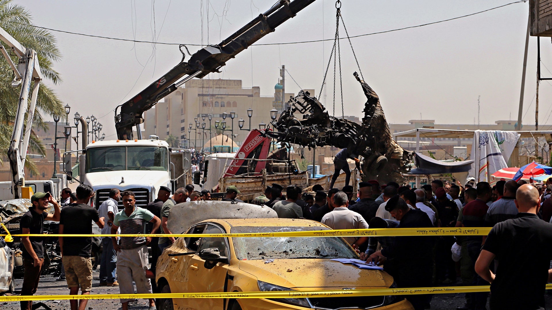 Iraqi security forces remove destroyed vehicles at the site of a deadly bomb attack, in Baghdad, Iraq