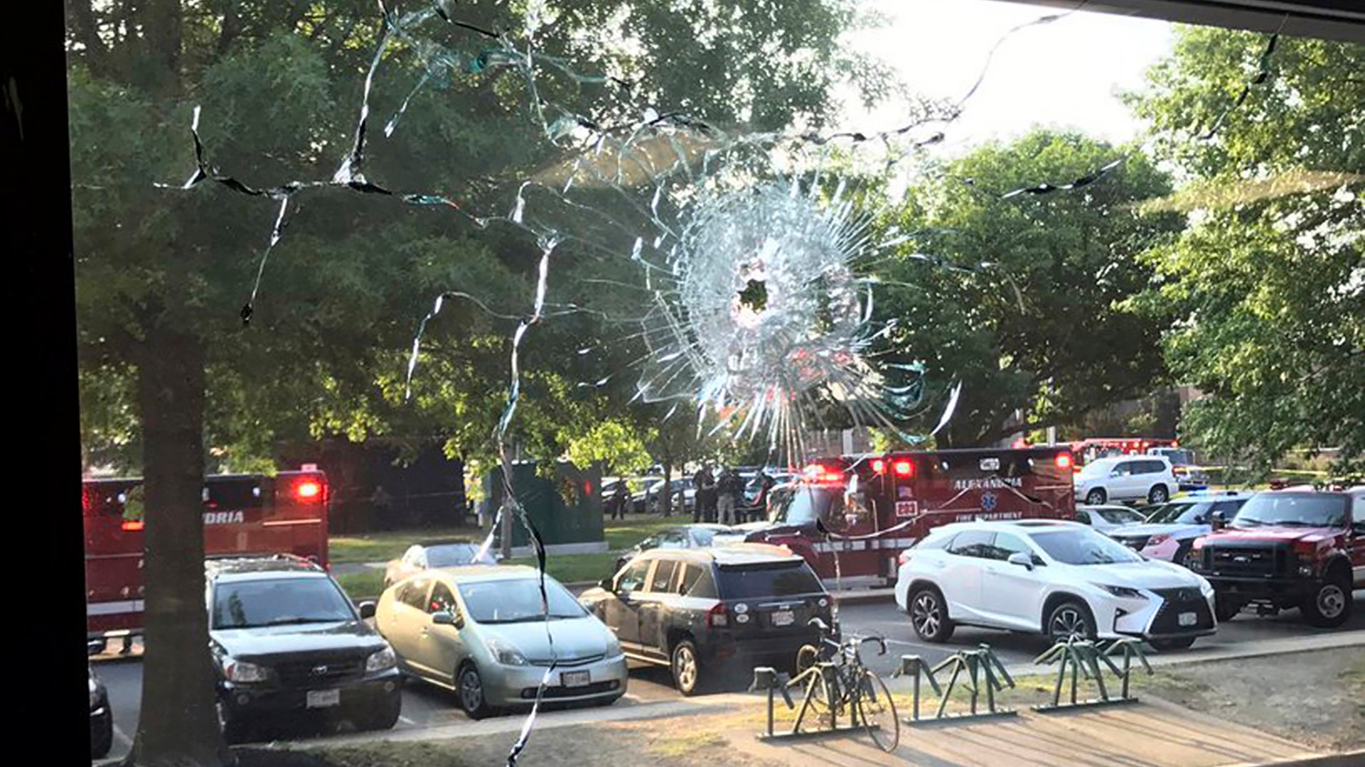 Emergency personnel are seen through a window with a bullet hole in Alexandria, Va., Wednesday