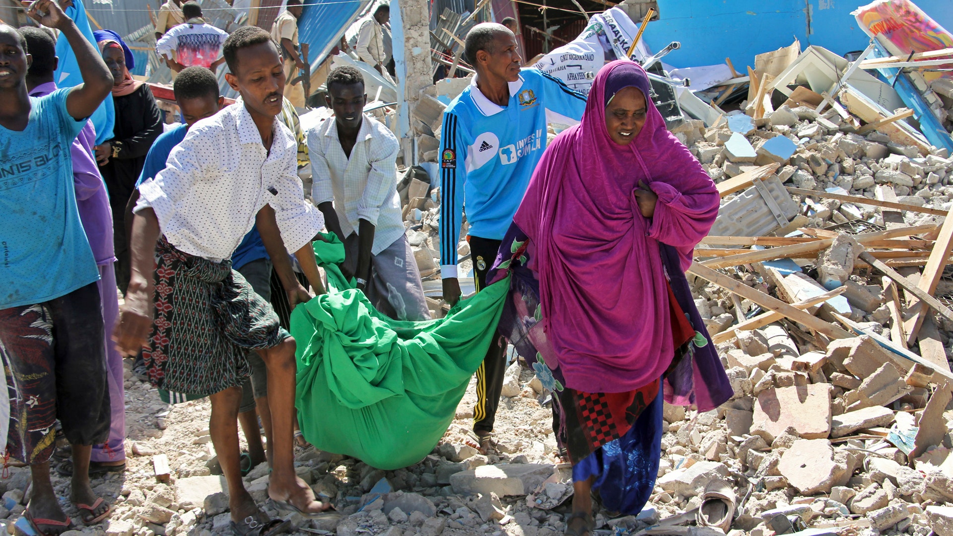 Somalis carry away the body of a civilian who was killed in a car bomb attack in Mogadishu, Somalia