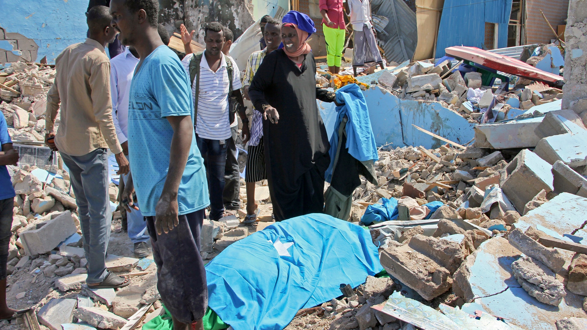 Somalis stand near the body of a civilian who was killed in a car bomb attack in Mogadishu, Somalia 