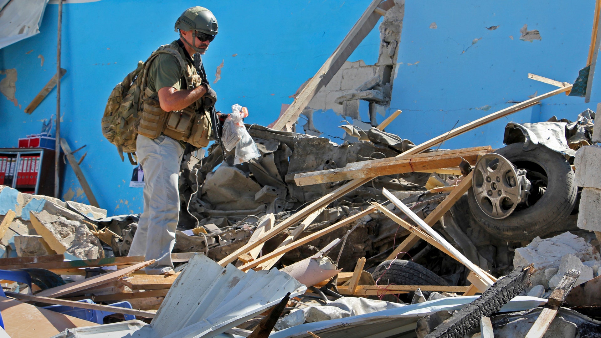 An unidentified armed member of foreign security personnel examines the scene of a car bomb attack in Mogadishu, Somalia 