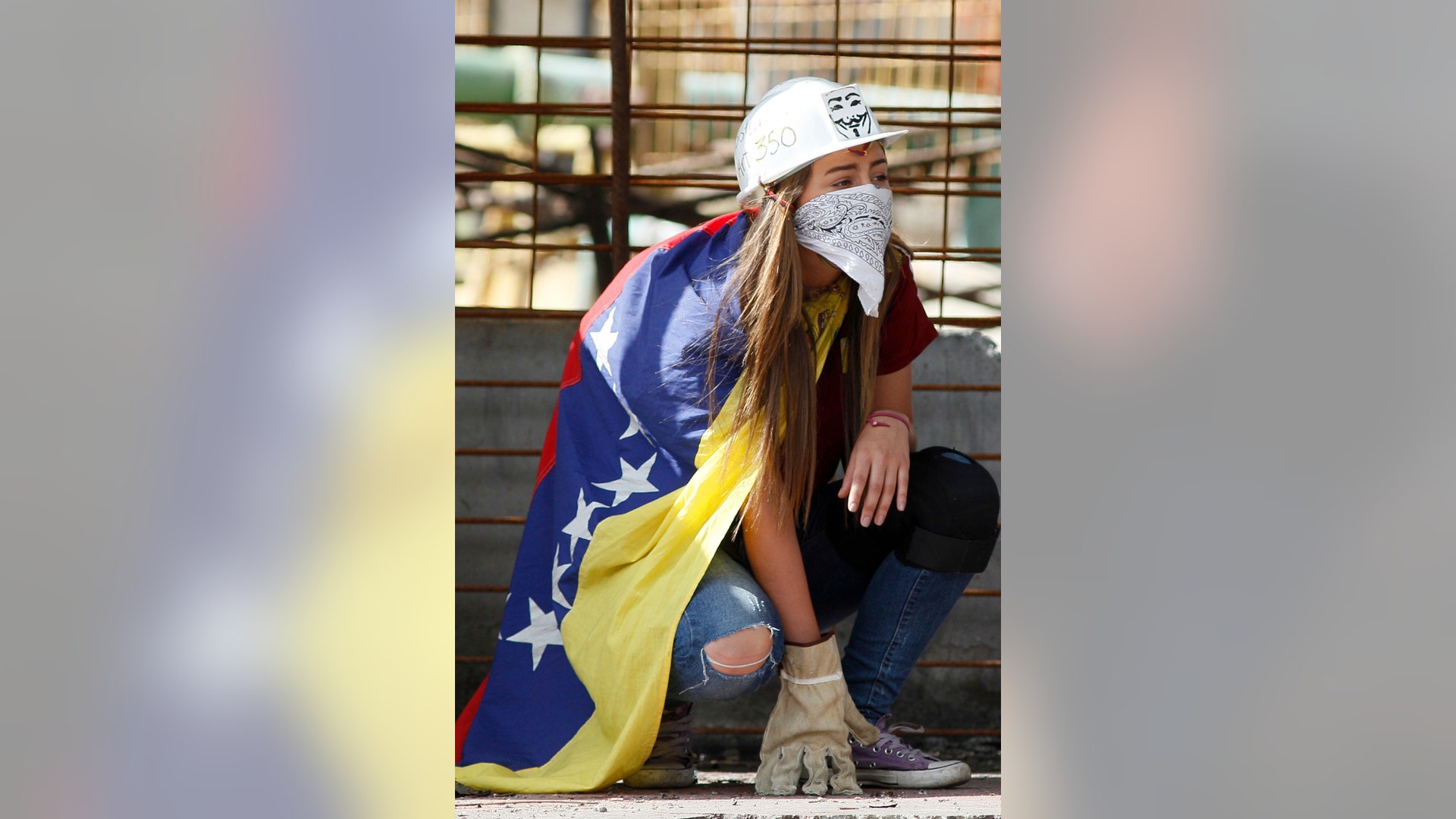An anti-government demonstrator wears a Venezuelan flag, helmet, bandana and gloves during clashes against the Bolivarian National Guard
