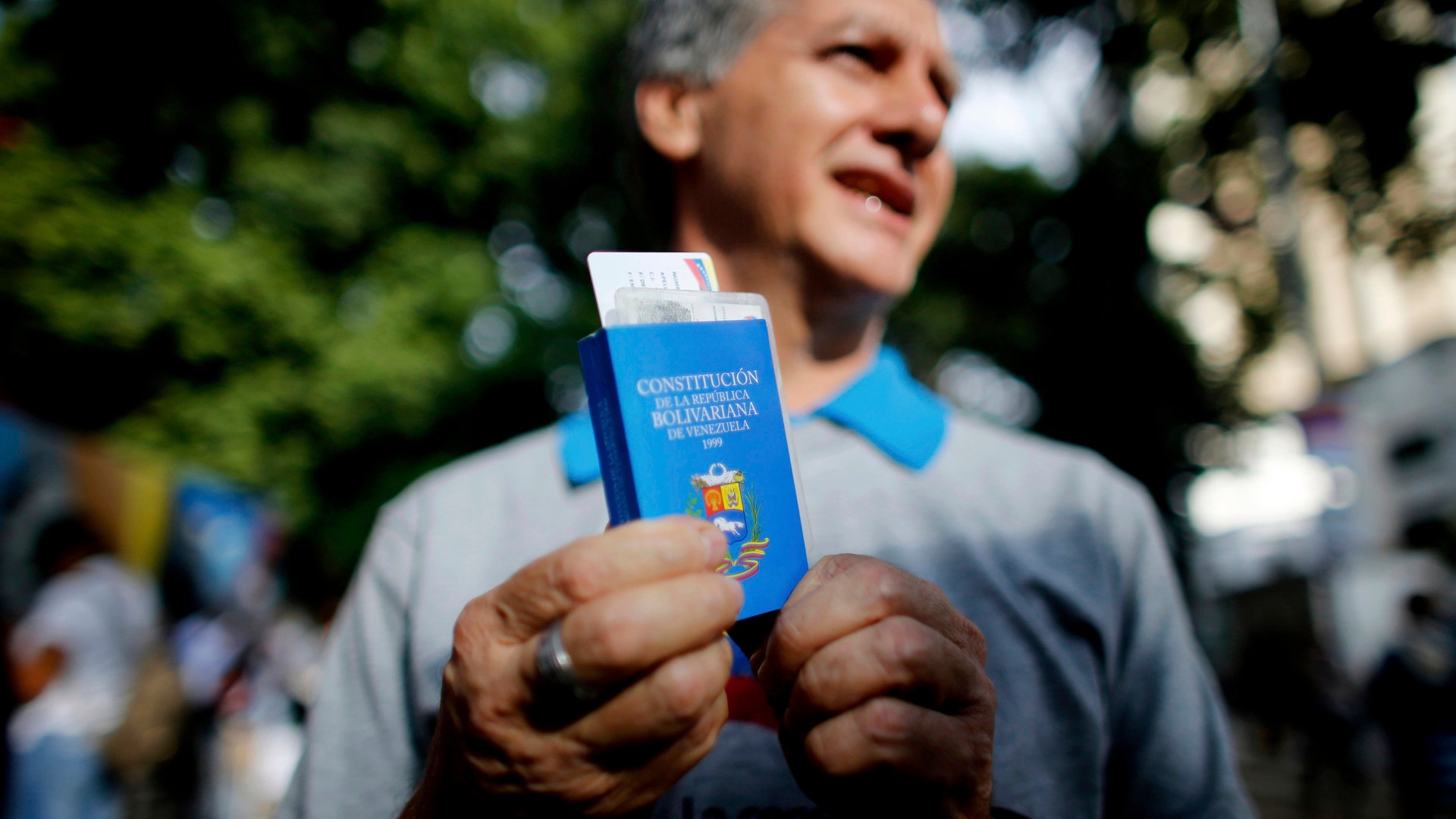 A man holds a copy of the Venezuelan Constitution as he waits to vote for the constitutional assembly outside of a poll station