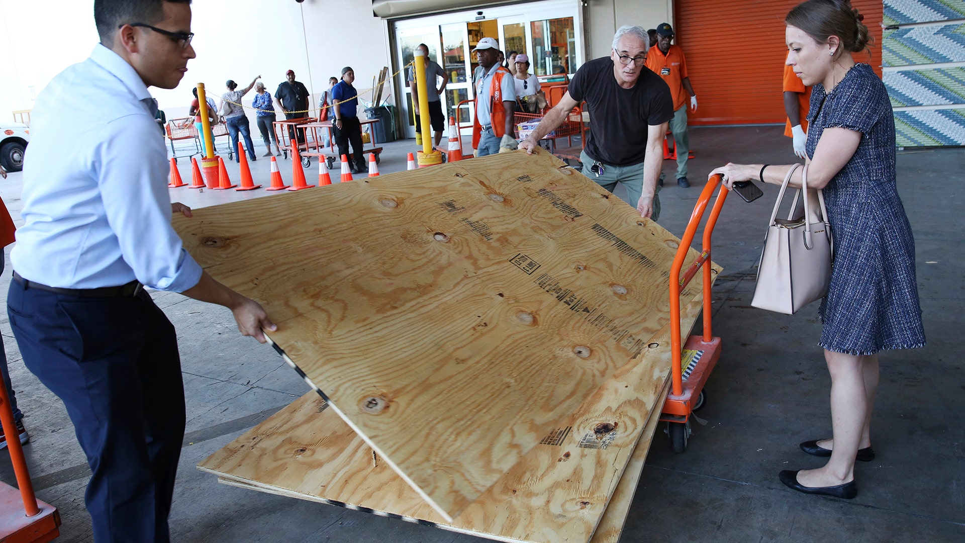 People load sheets of plywood into their car at The Home Depot store in North Miami, Fla., Wednesday