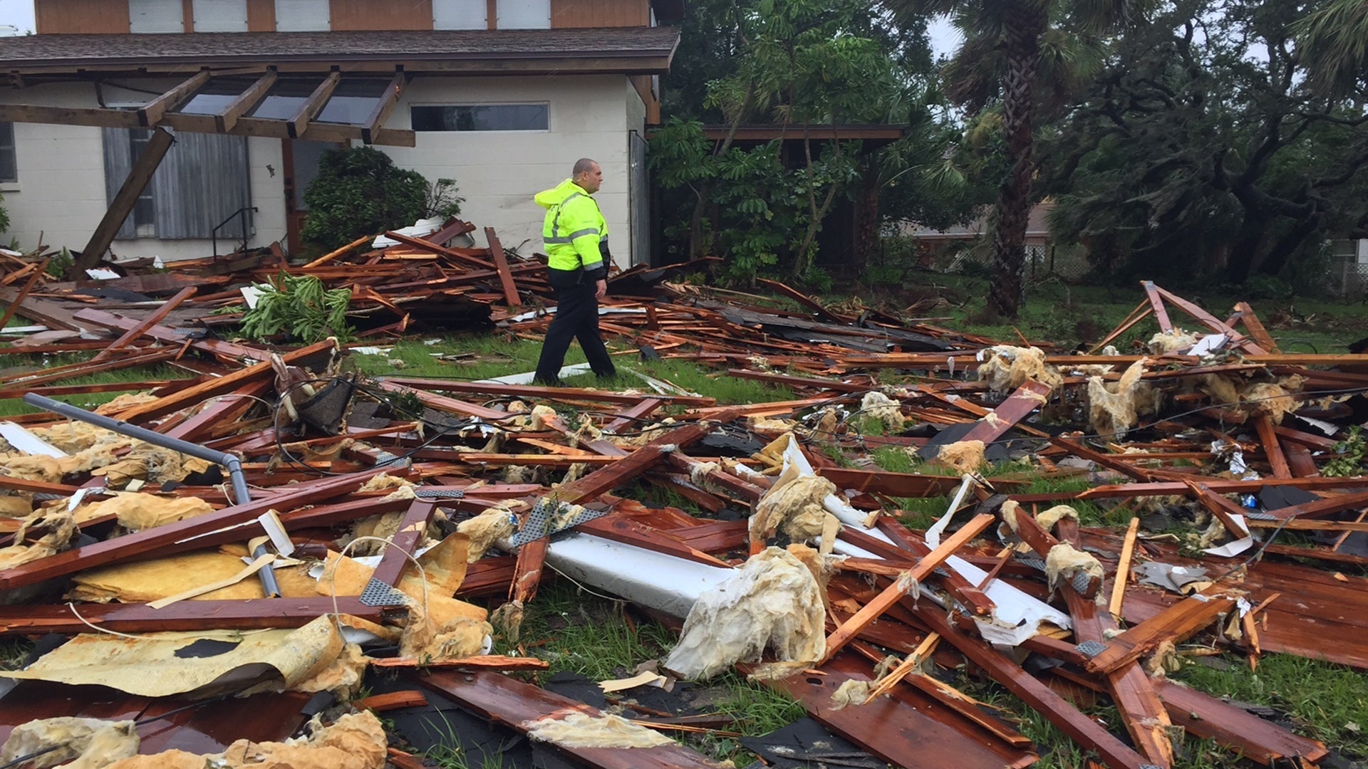 Palm Bay officer Dustin Terkoski walks over tornado damage to a home in Palm Point Subdivision in Brevard County, Fla., Sunday