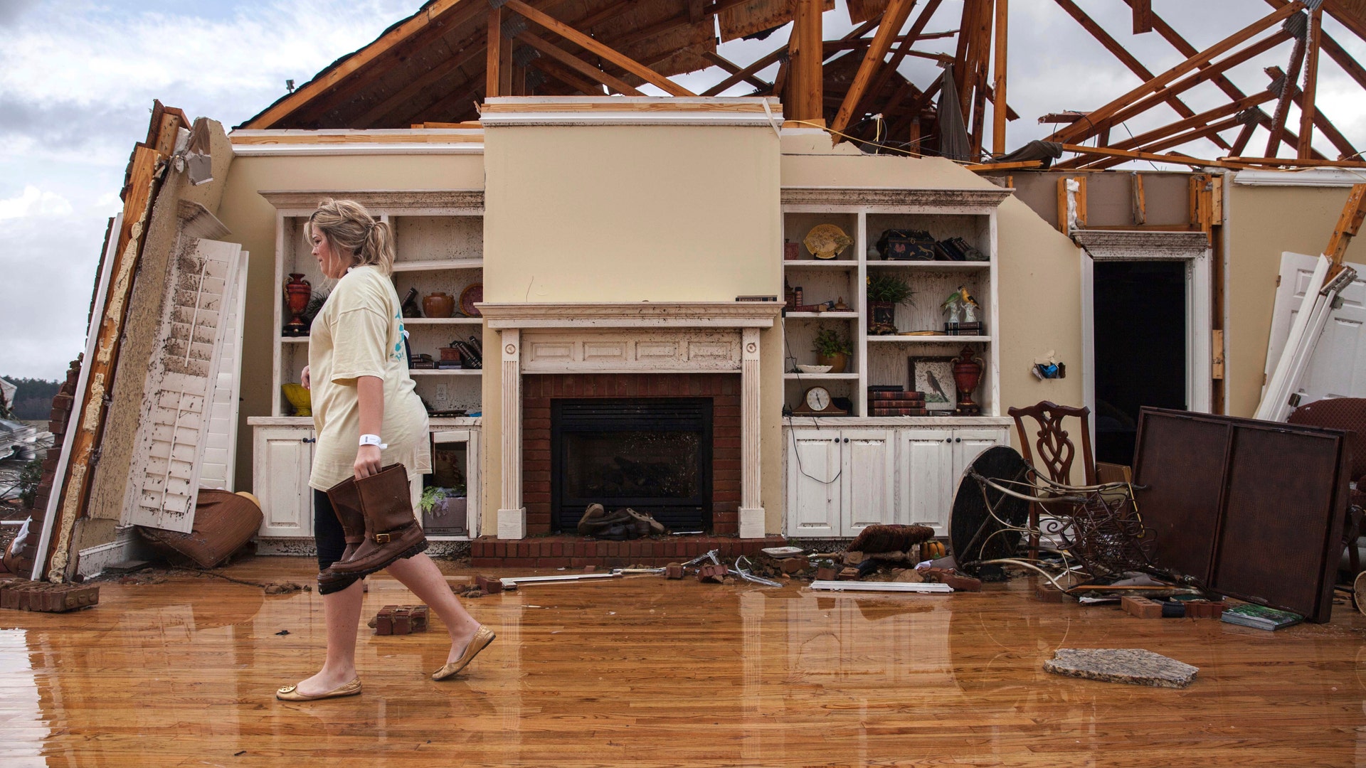 Jenny Bullard carries a pair of boots from her home that was damaged by a tornado, Sunday, Jan. 22, 2017, in Adel, Ga. 