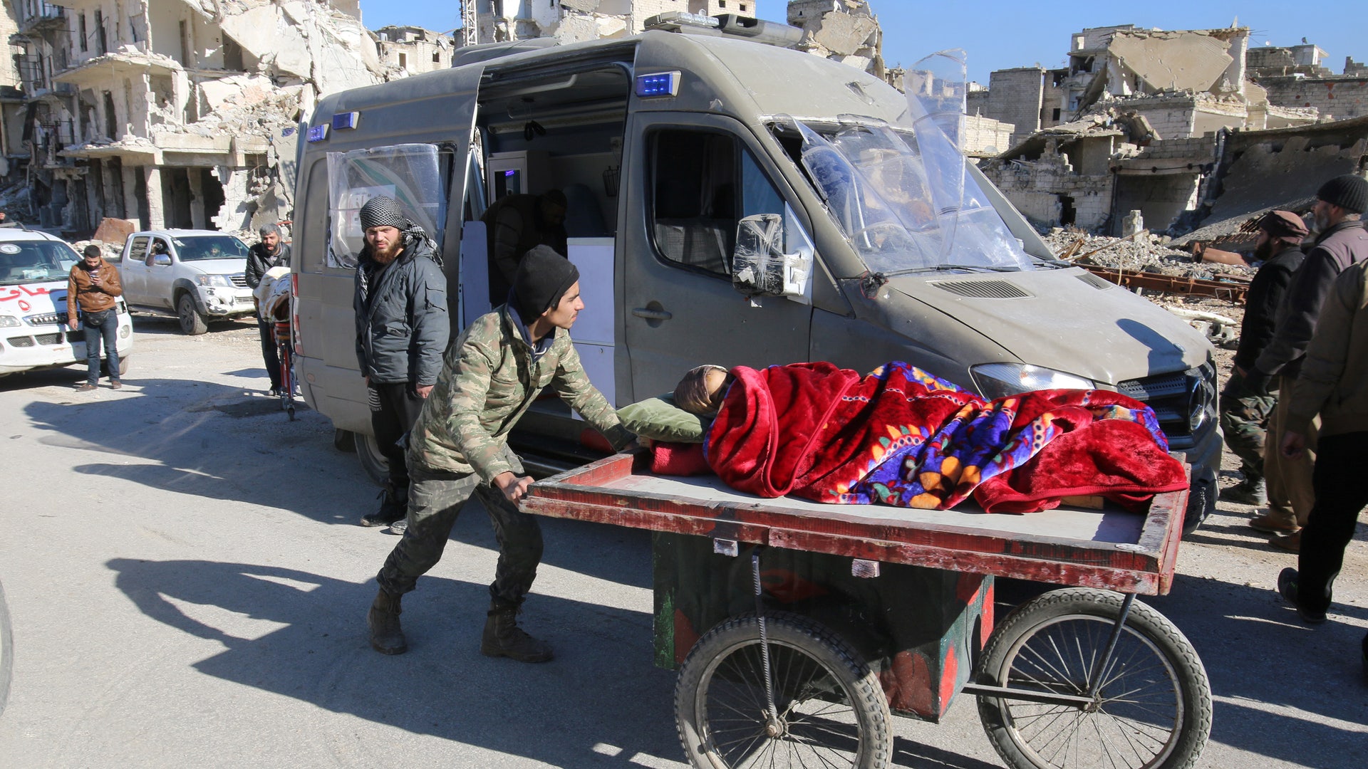 A man pushes a cart with a woman lying on it as vehicles wait to evacuate people from a rebel-held sector of eastern Aleppo, Syria December 15, 2016. 