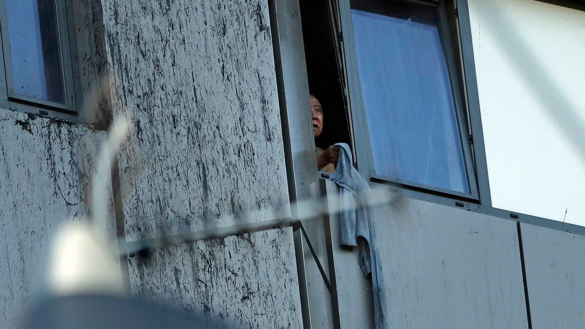 A person peers out of a window from the building on fire in London