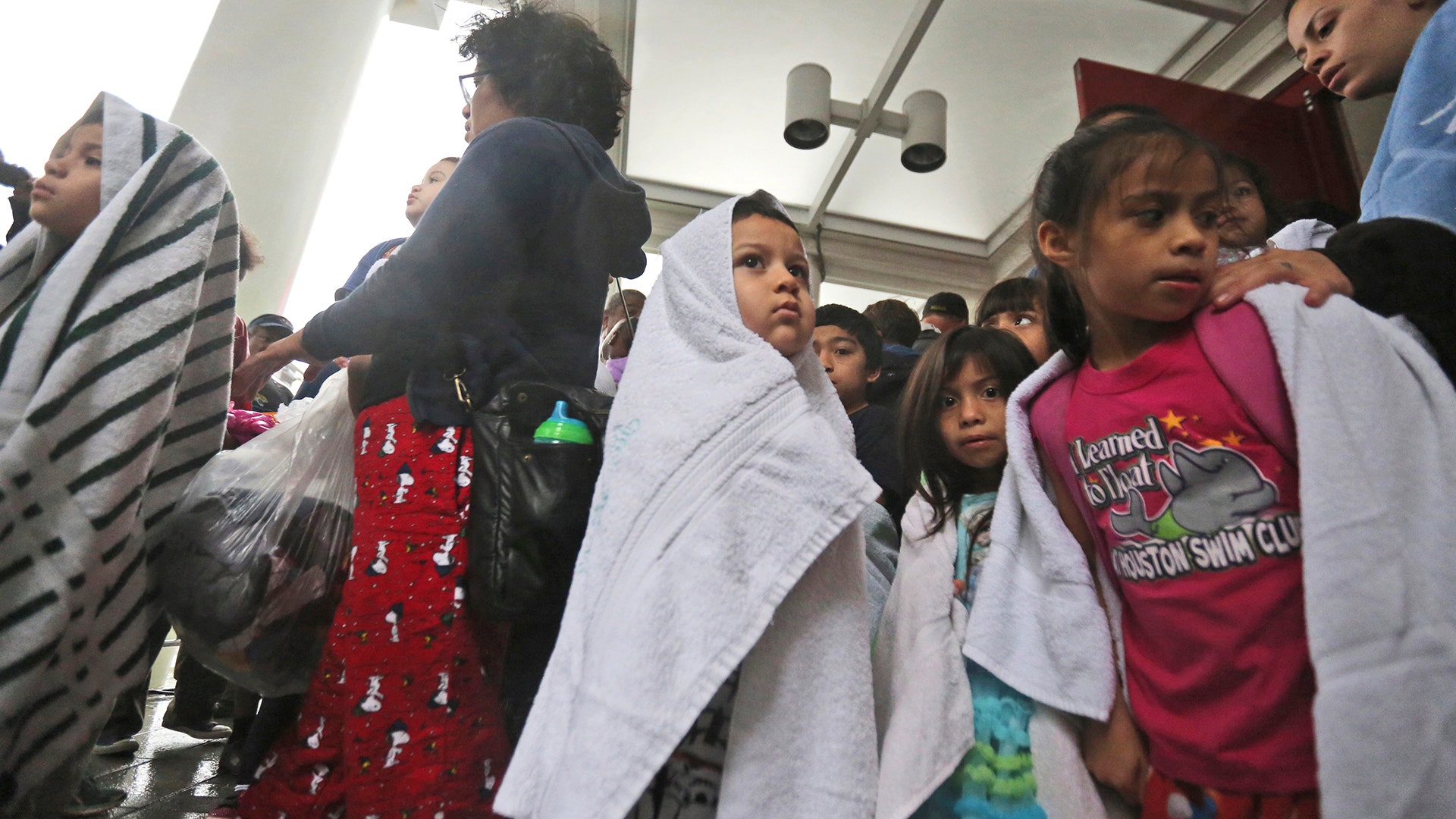 Children and adults wait to get into the George R. Brown Convention Center after evacuating during Tropical Storm Harvey in Houston, on Tuesday