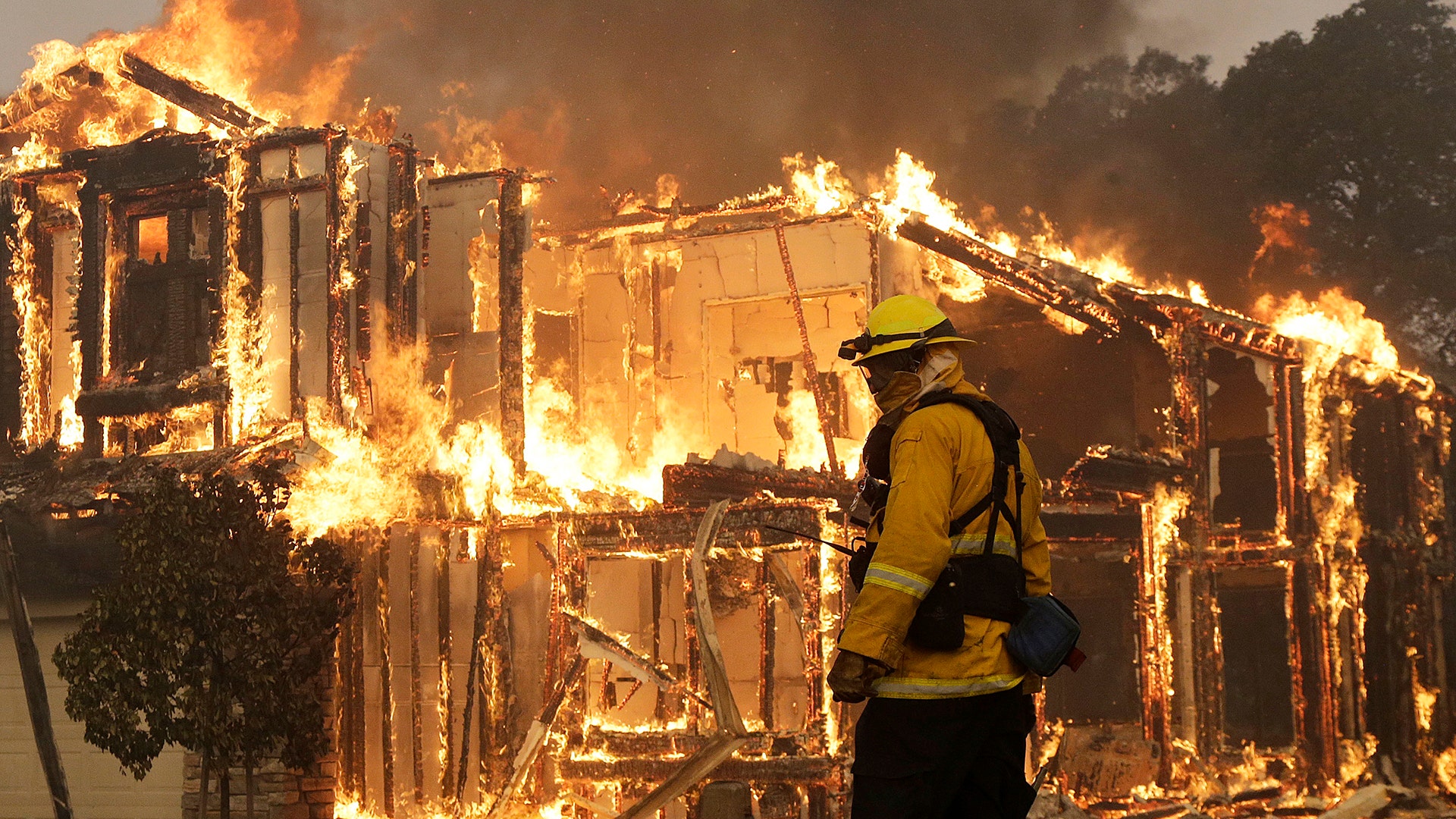 A firefighter monitors a house burning in Santa Rosa