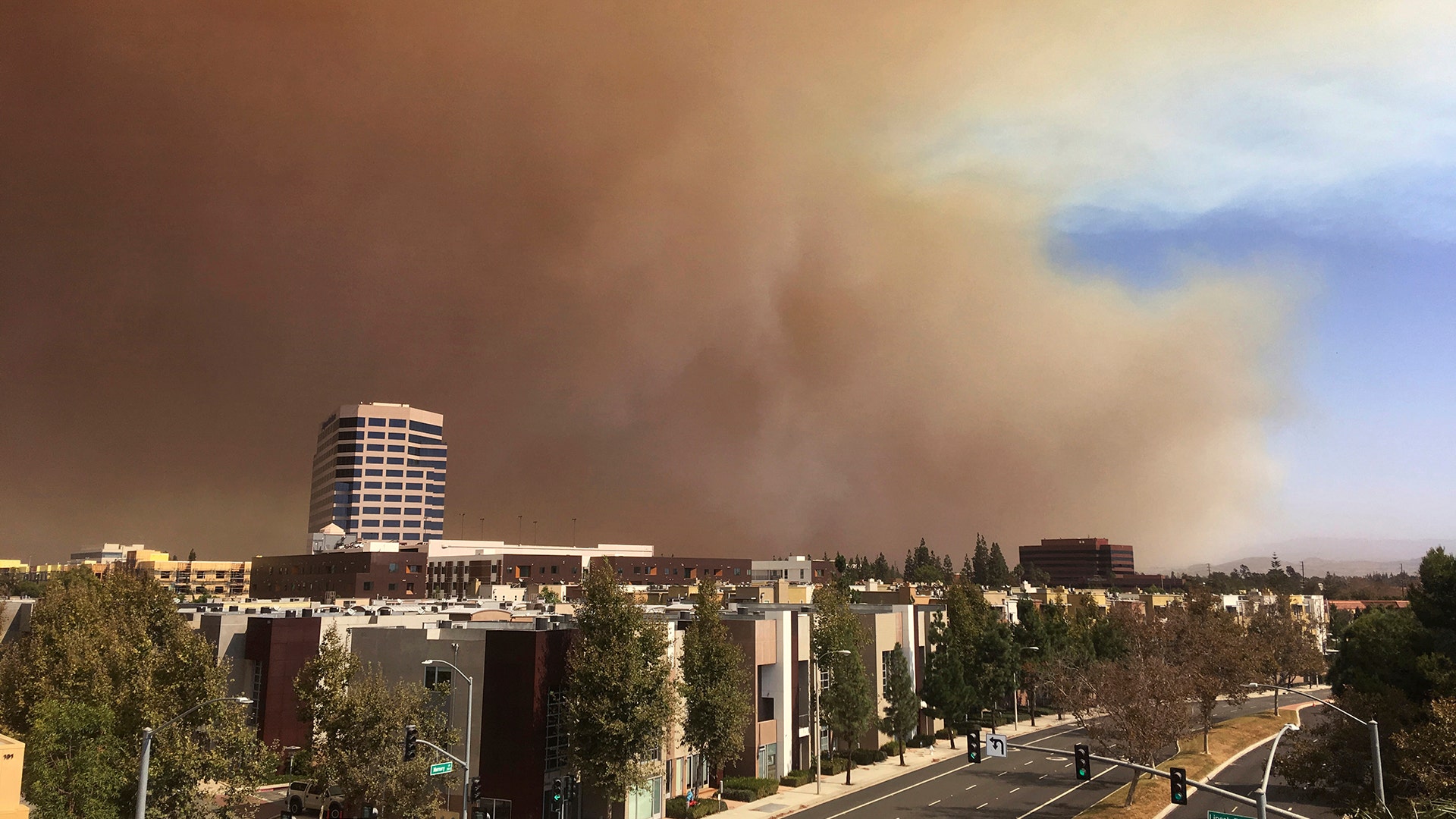 A large plume of smoke from a brush fire rises over the city of Orange