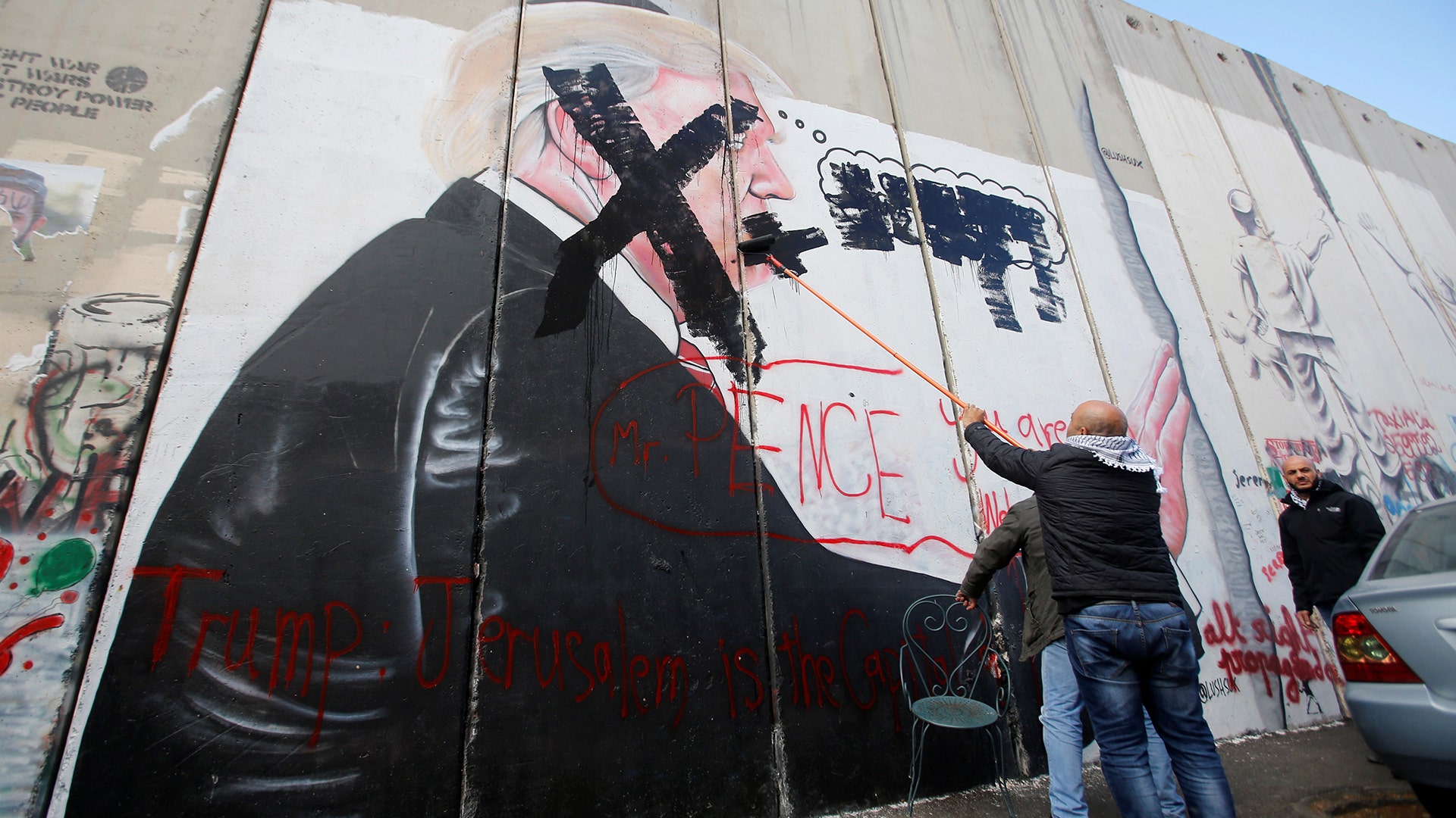 A Palestinian man crosses out a mural depicting U.S. President Donald Trump on the Israeli barrier, in Bethlehem, December 7